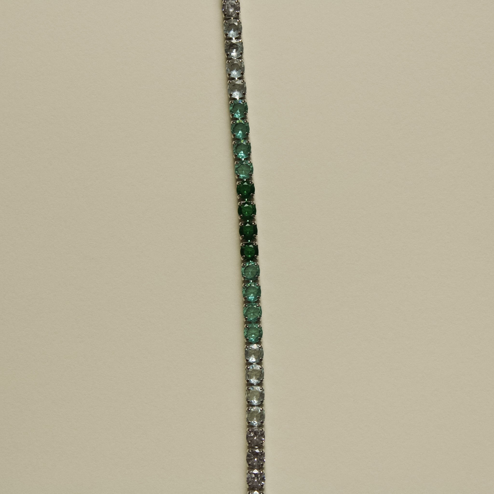 Tennis bracelet with vertical line of green and clear stones, no clasp visible