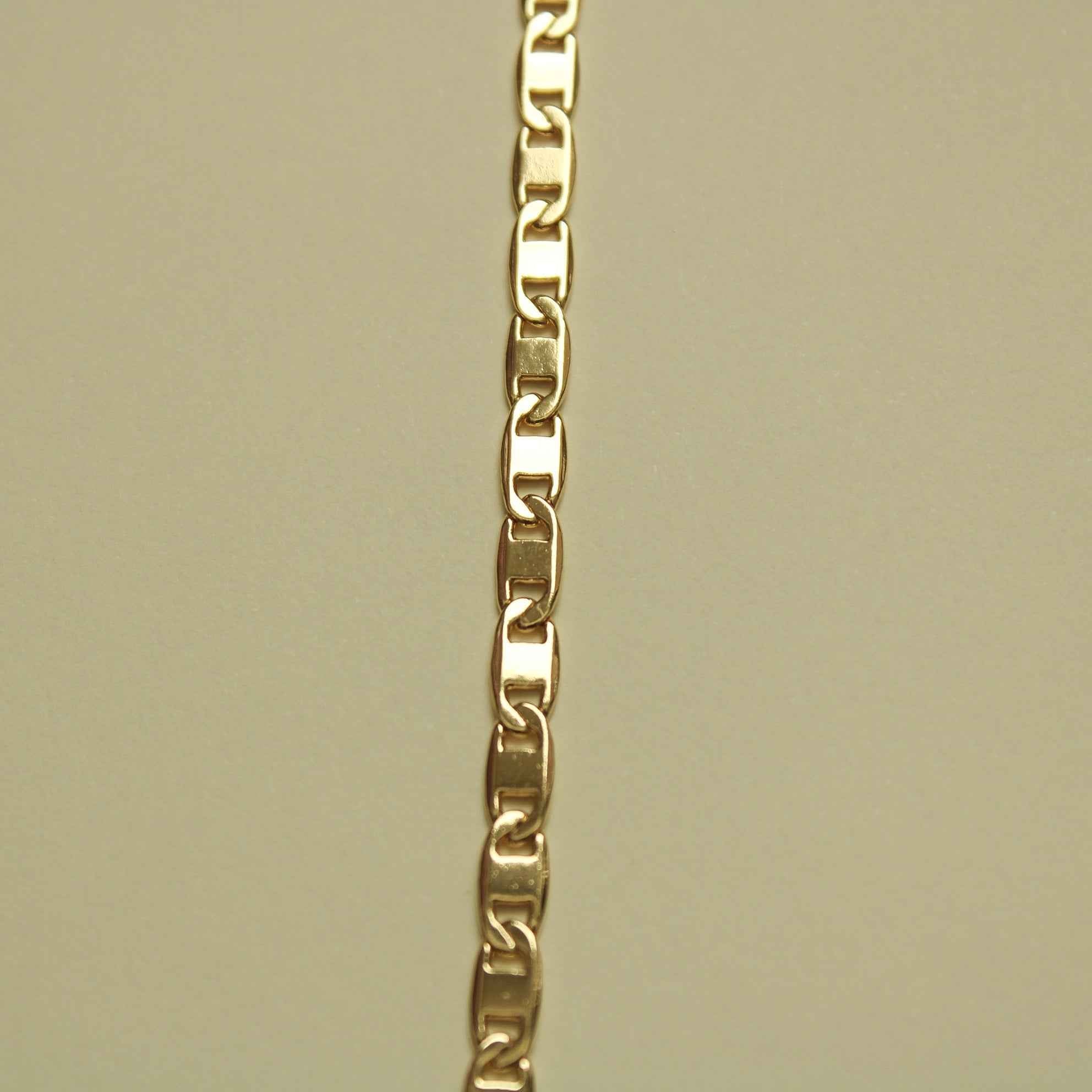 Gold-tone chain bracelet links with smooth polished surfaces; side view.