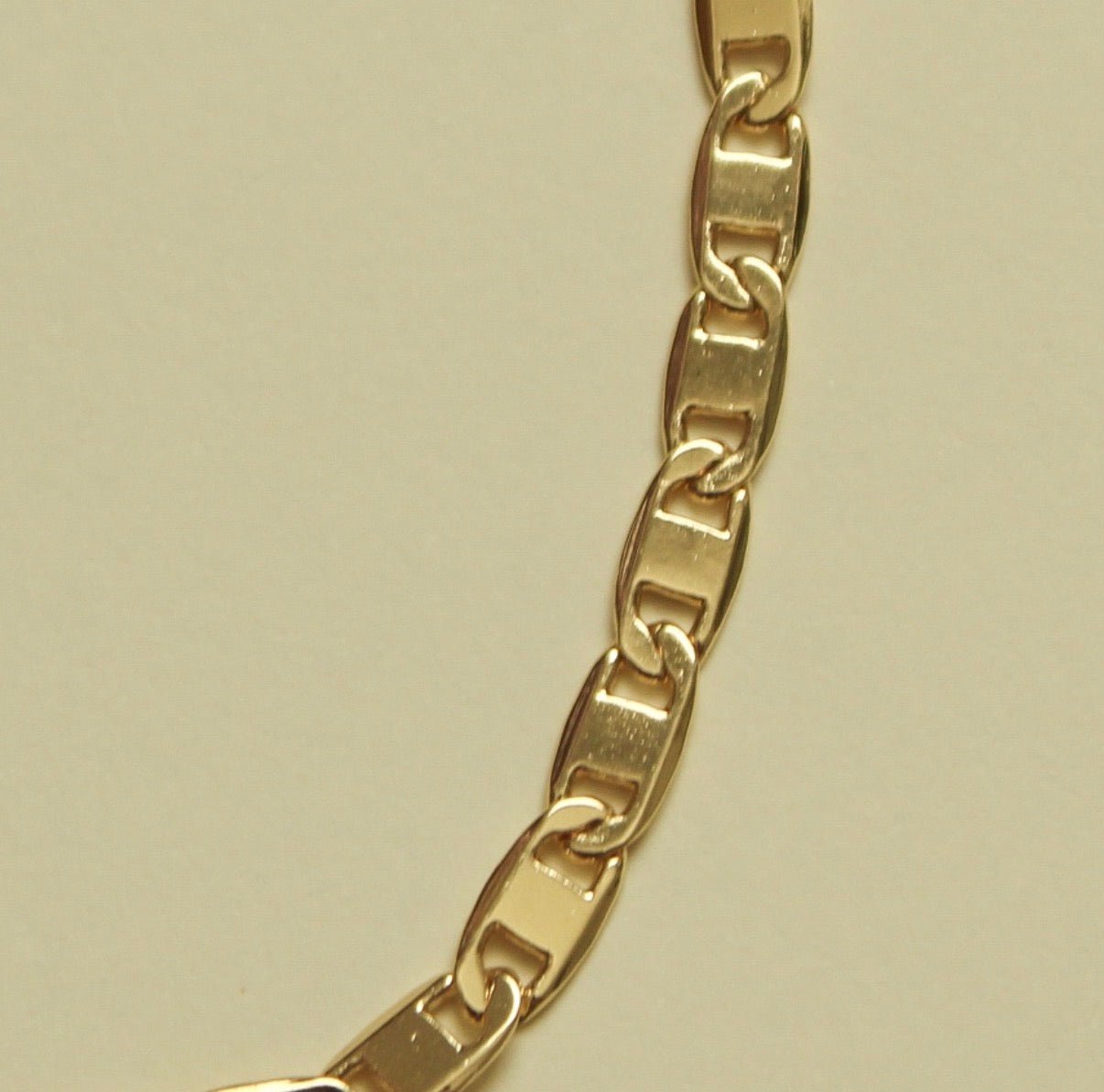 Gold-tone anchor link bracelet chain detail with clasp end; side close-up.