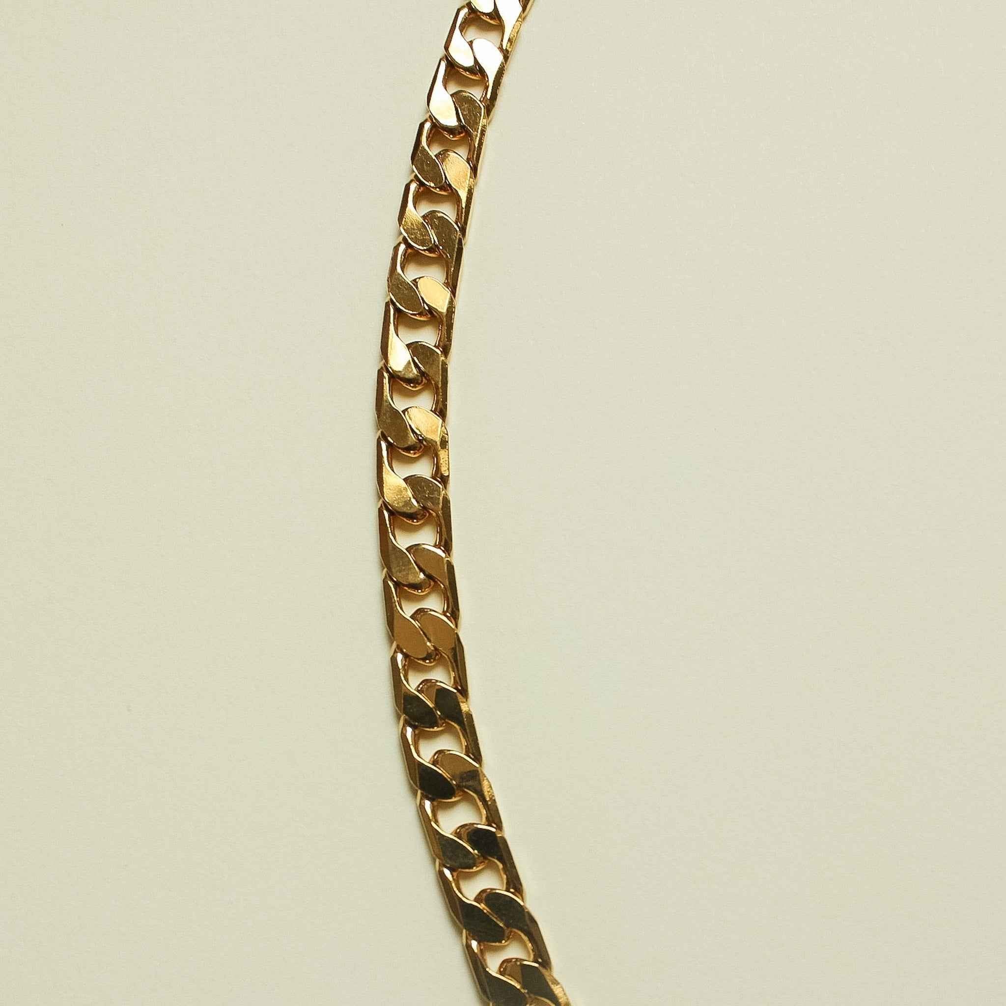 Gold-tone flat Cuban link chain necklace, vertical side view of interlocking links