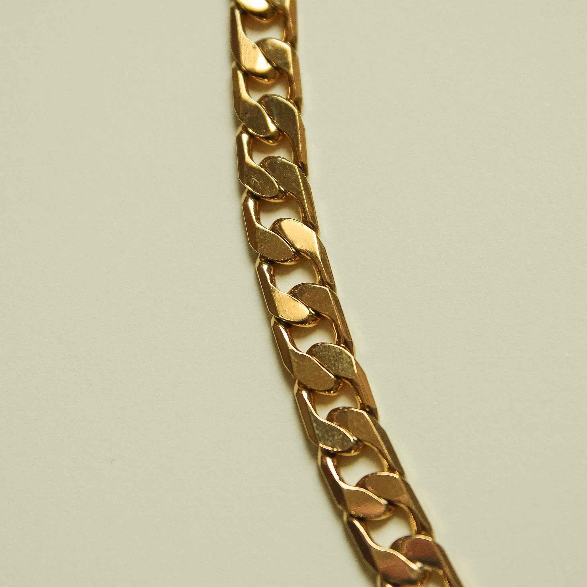 Gold-tone flat Cuban link chain necklace, close-up of interlocking links