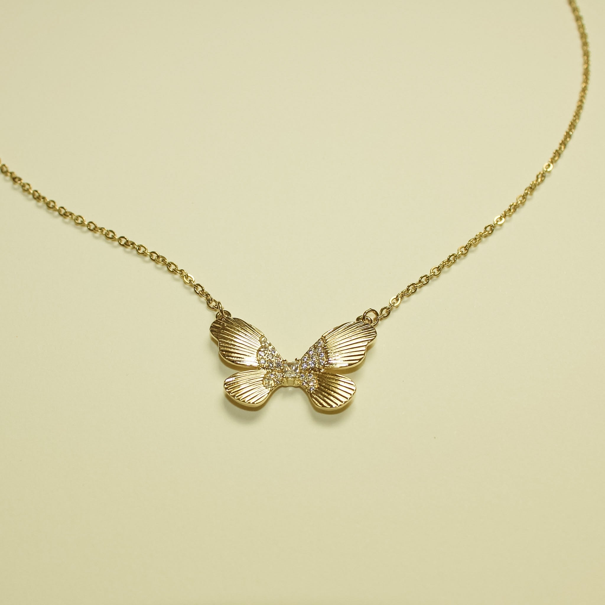 Gold-plated butterfly CZ necklace pendant centered on chain, fluted wings.