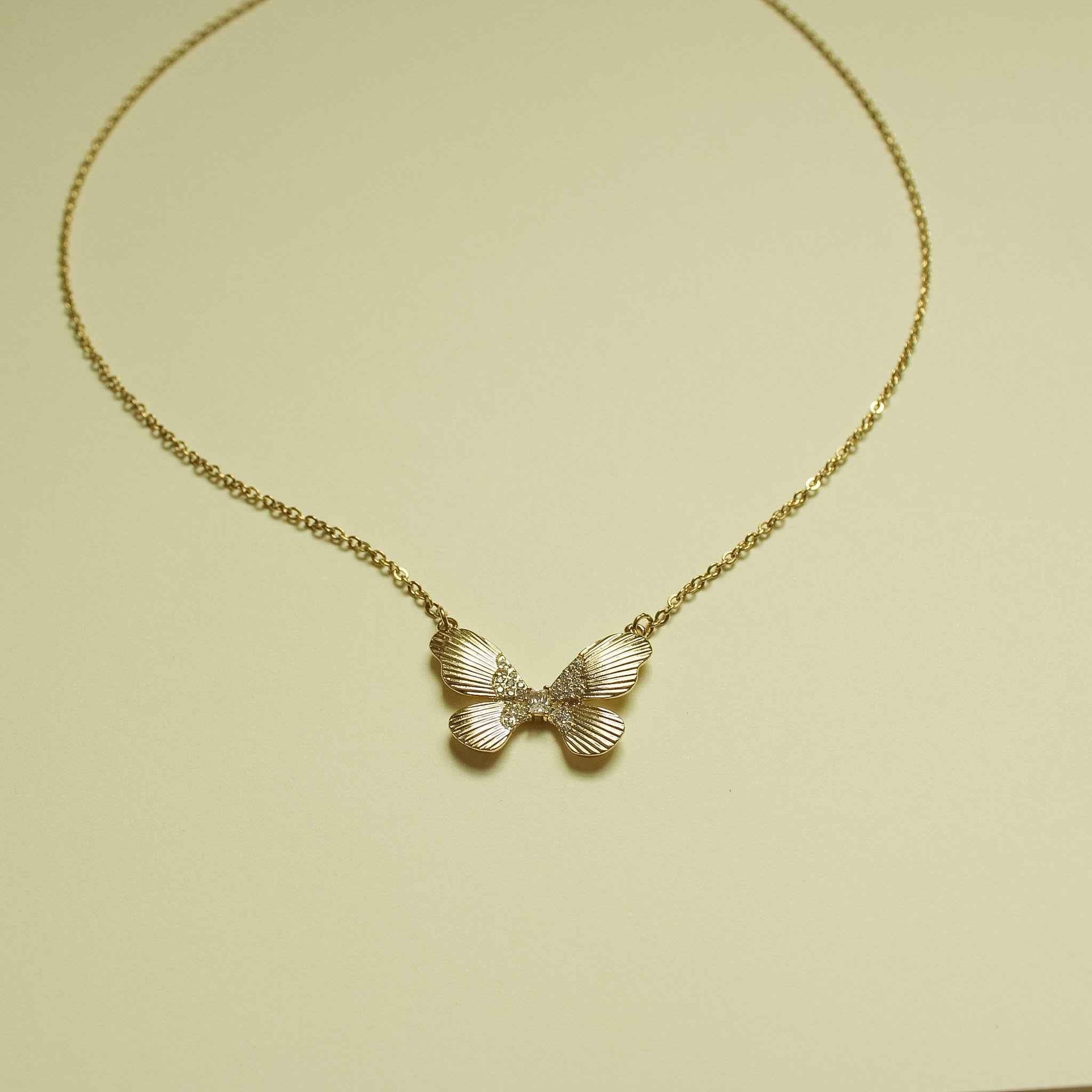 Gold-plated butterfly CZ pendant necklace with three-wing fluted design on chain.