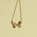 Gold-plated butterfly CZ necklace with three fluted wings, hanging on chain.