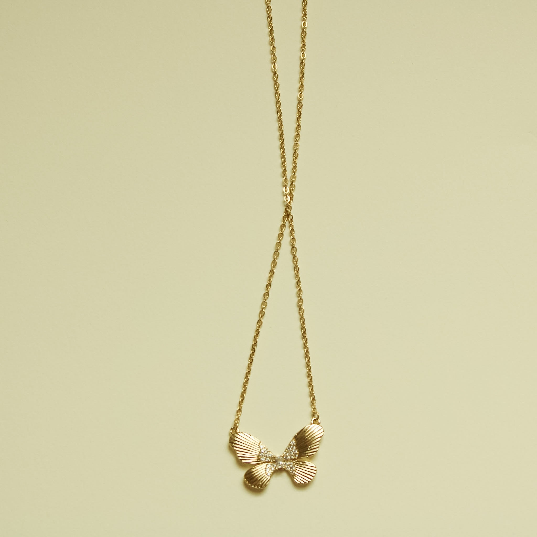 Gold-plated butterfly CZ pendant on slim chain, fluted wing details.