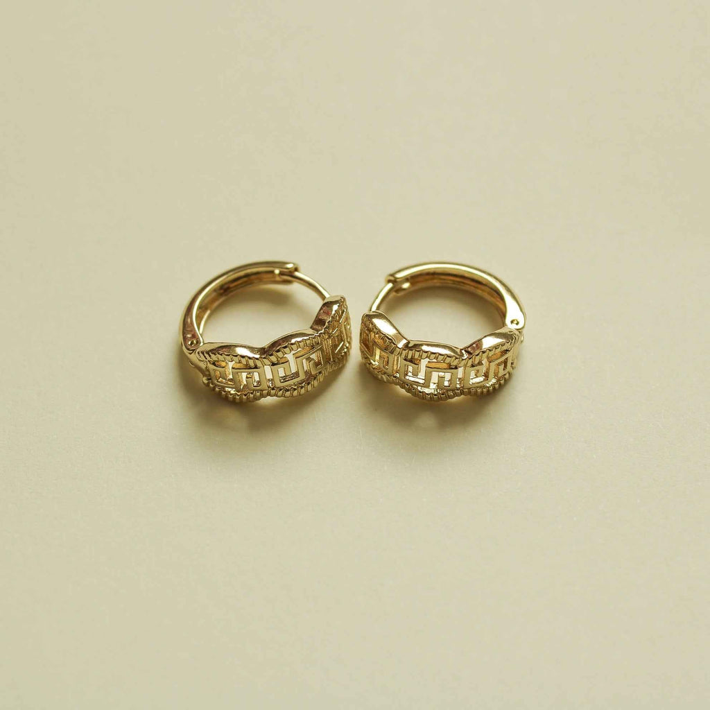 Gold huggie hoop earrings with Greek key pattern, angled view of both