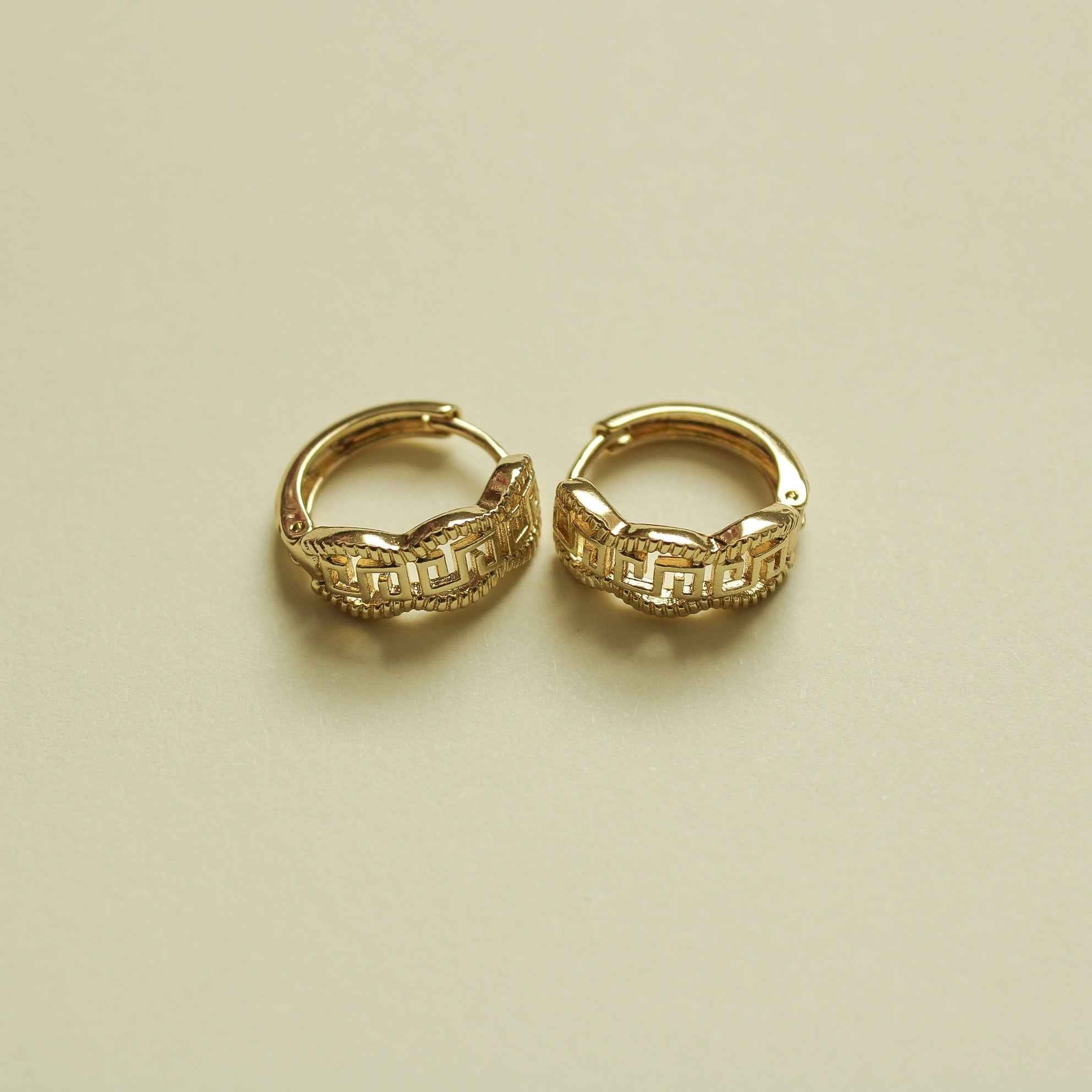 Gold huggie hoop earrings with Greek key pattern, angled view of both