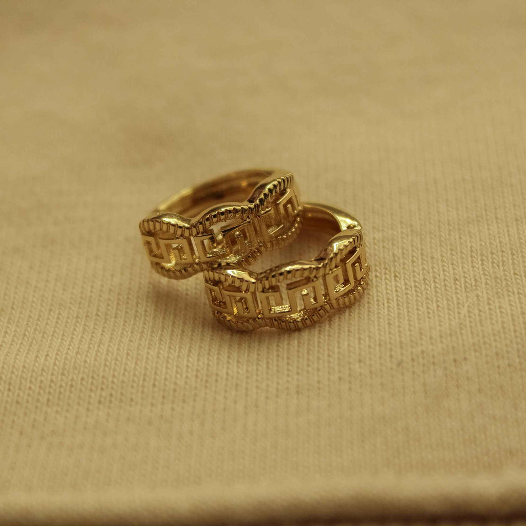 Gold huggie hoop earring, close-up of Greek key textured engraving
