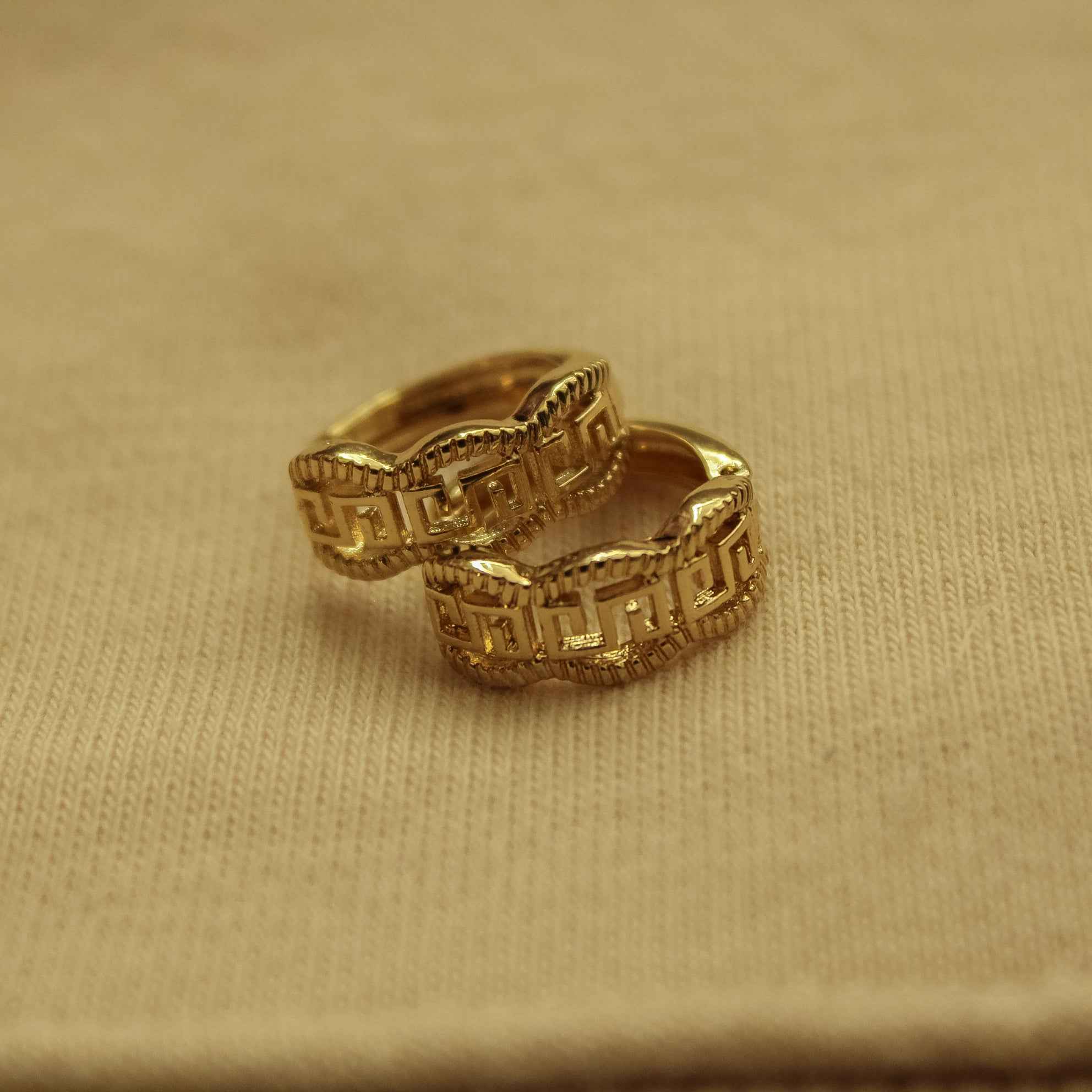 Gold huggie hoop earring, close-up of Greek key textured engraving