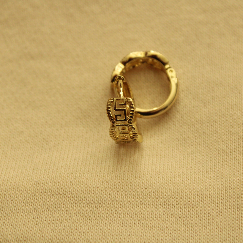 Gold huggie hoop earring clasp area with Greek key motif