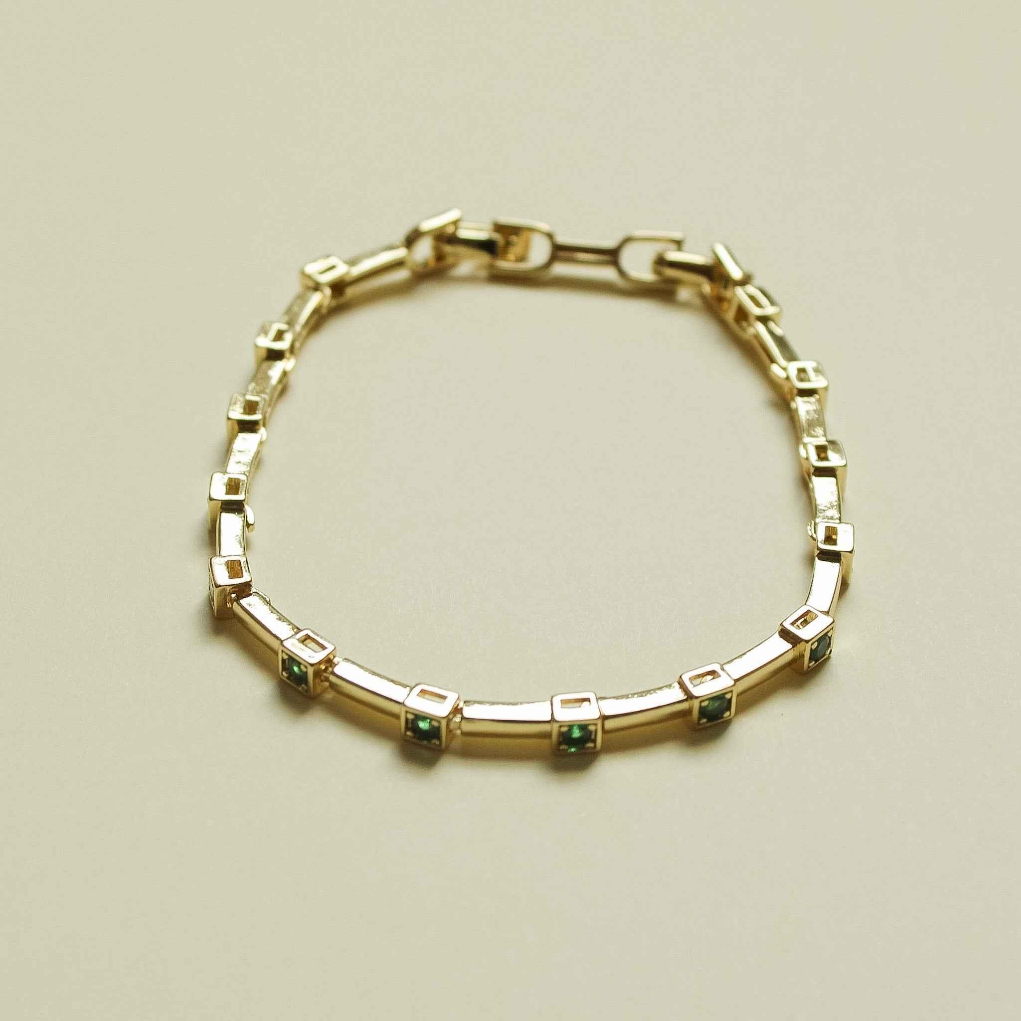 Gold-tone bar link bracelet with small square green accent stones