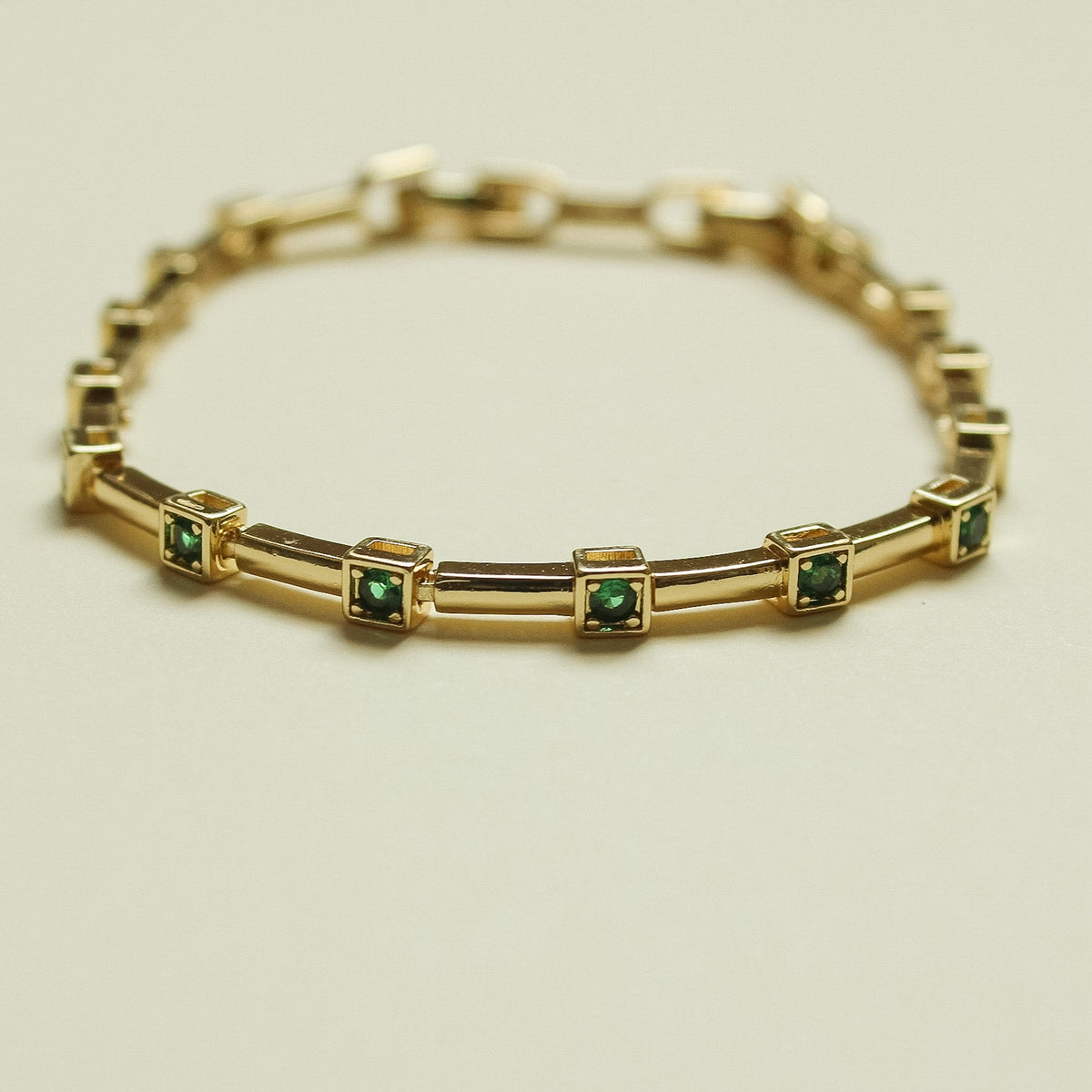 Gold-tone bar link bracelet with green square stones in bezel frames