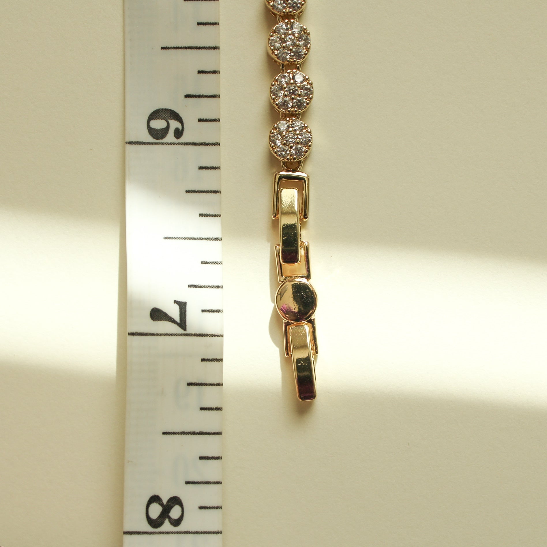 Gold bracelet clasp with pavé round stones and a hinged bar closure.