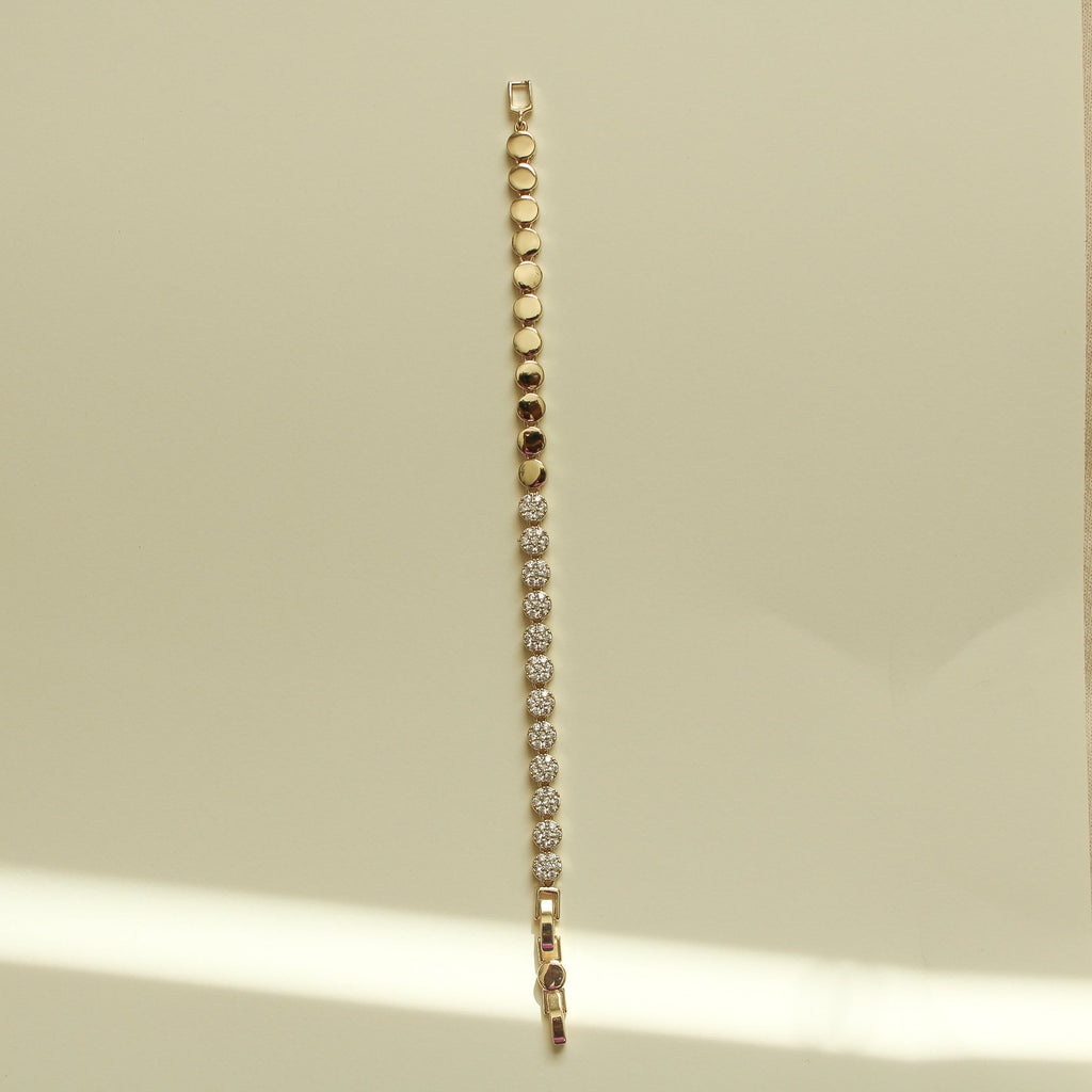 Gold tennis bracelet with pavé round-stone stations and a slim chain edge.