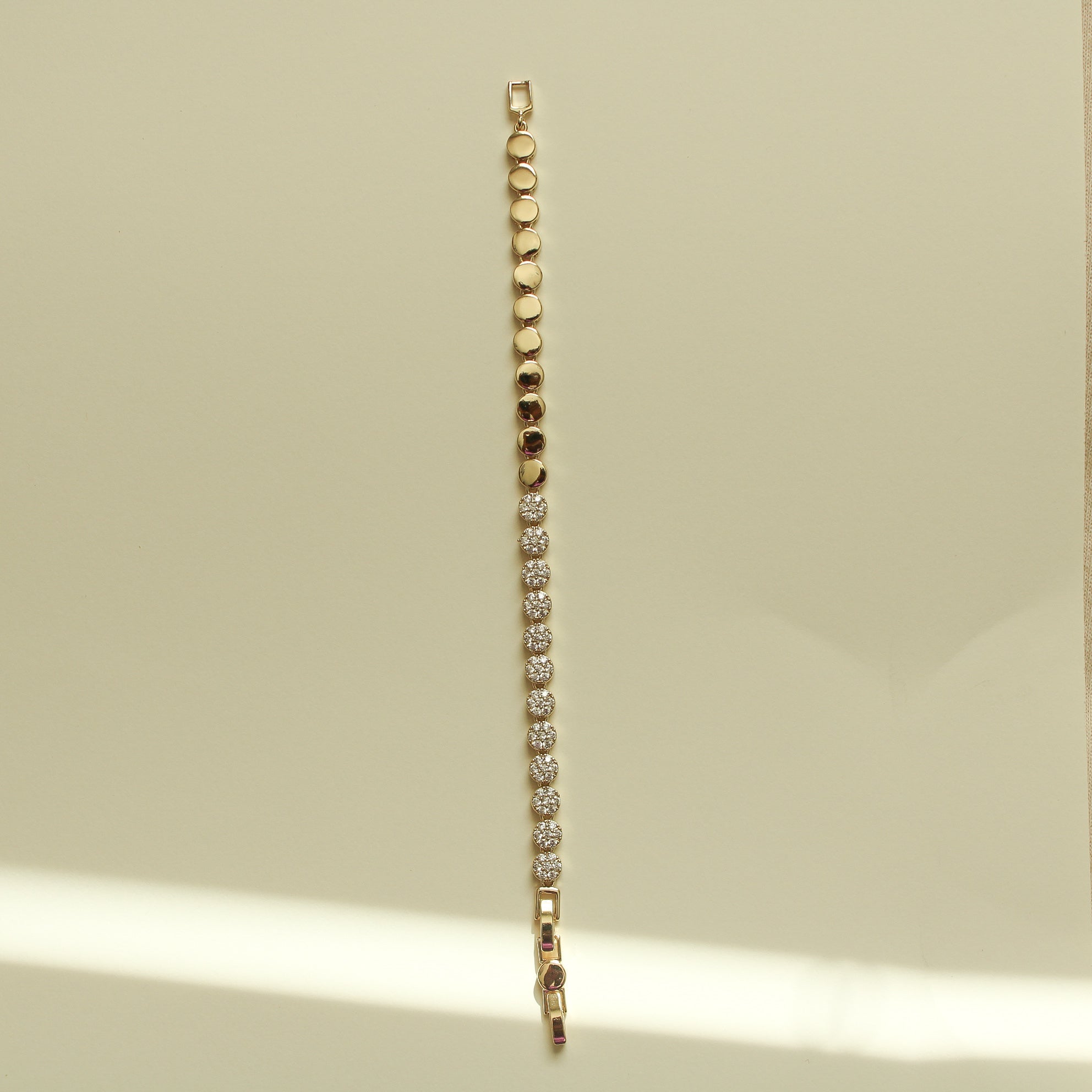 Gold tennis bracelet with pavé round-stone stations and a slim chain edge.