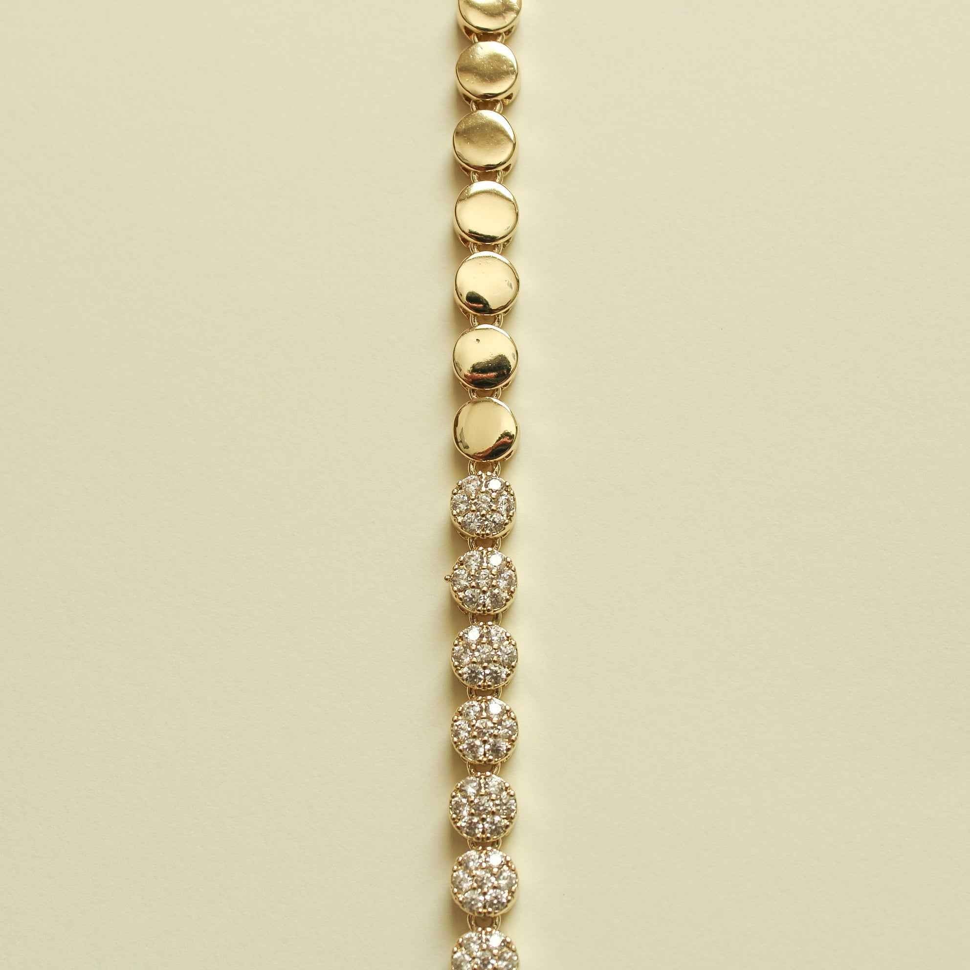 Pavé tennis bracelet strand with round pavé stations and gold disc links at top.