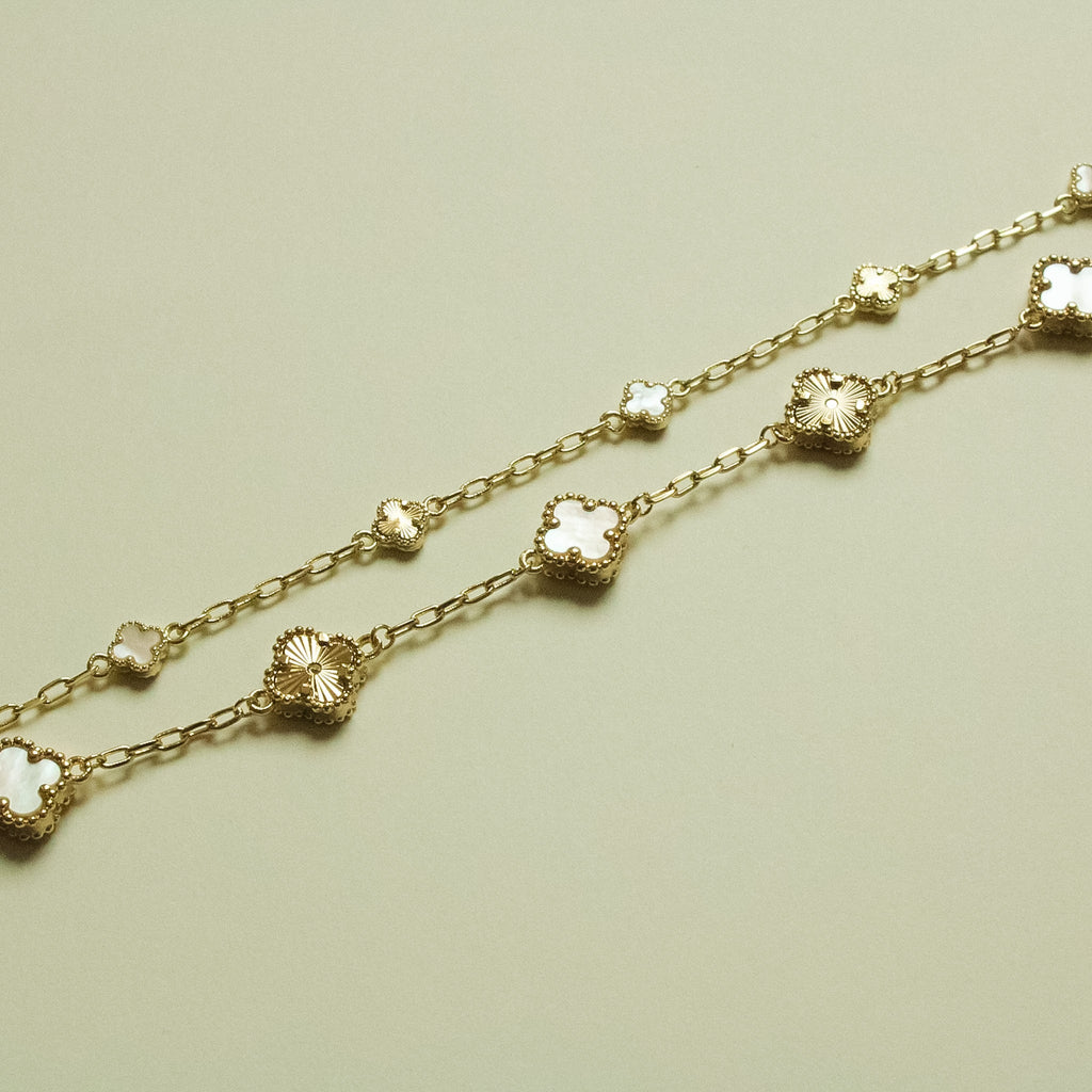 Gold bracelet strand with small clover charms and mother-of-pearl inlays