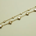 Gold bracelet strand with small clover charms and mother-of-pearl inlays