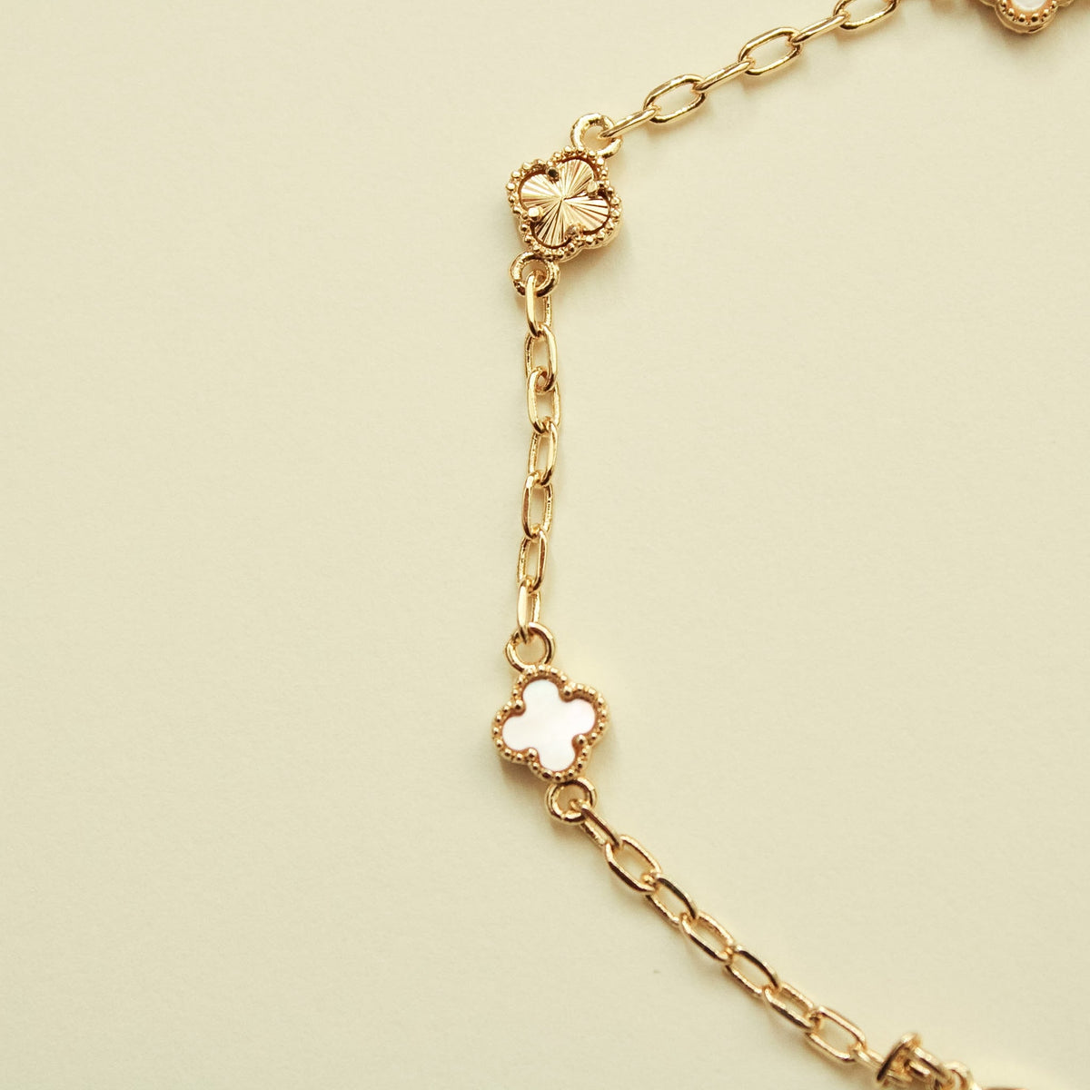 Gold bracelet with clover charm stations and mother-of-pearl inlays