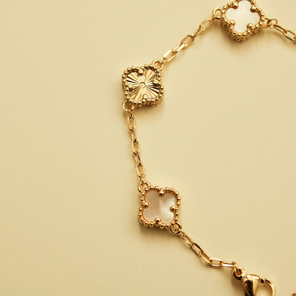 Gold bracelet with clover charms and mother-of-pearl inlays along linked chain