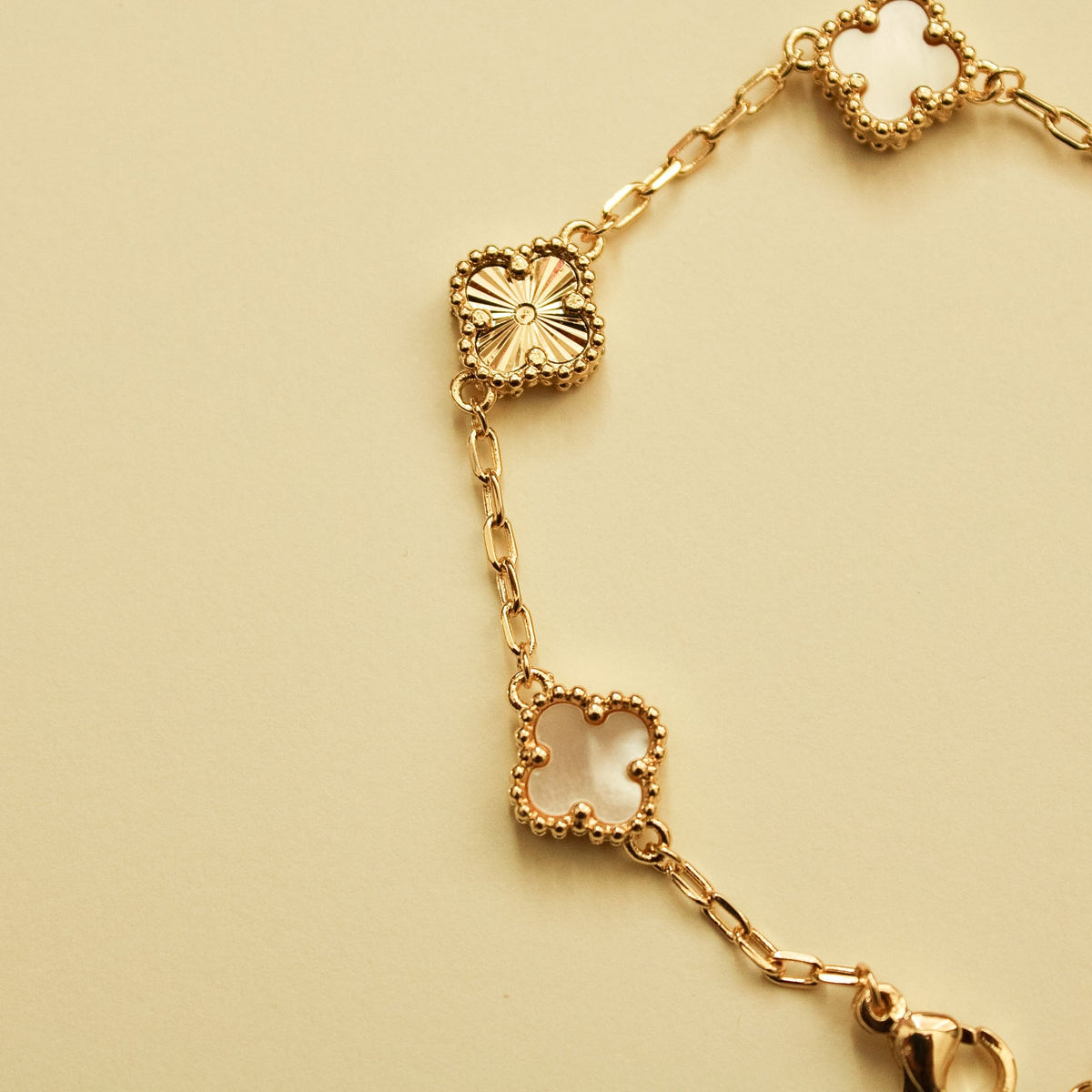 Gold bracelet with clover charms and mother-of-pearl inlays along linked chain