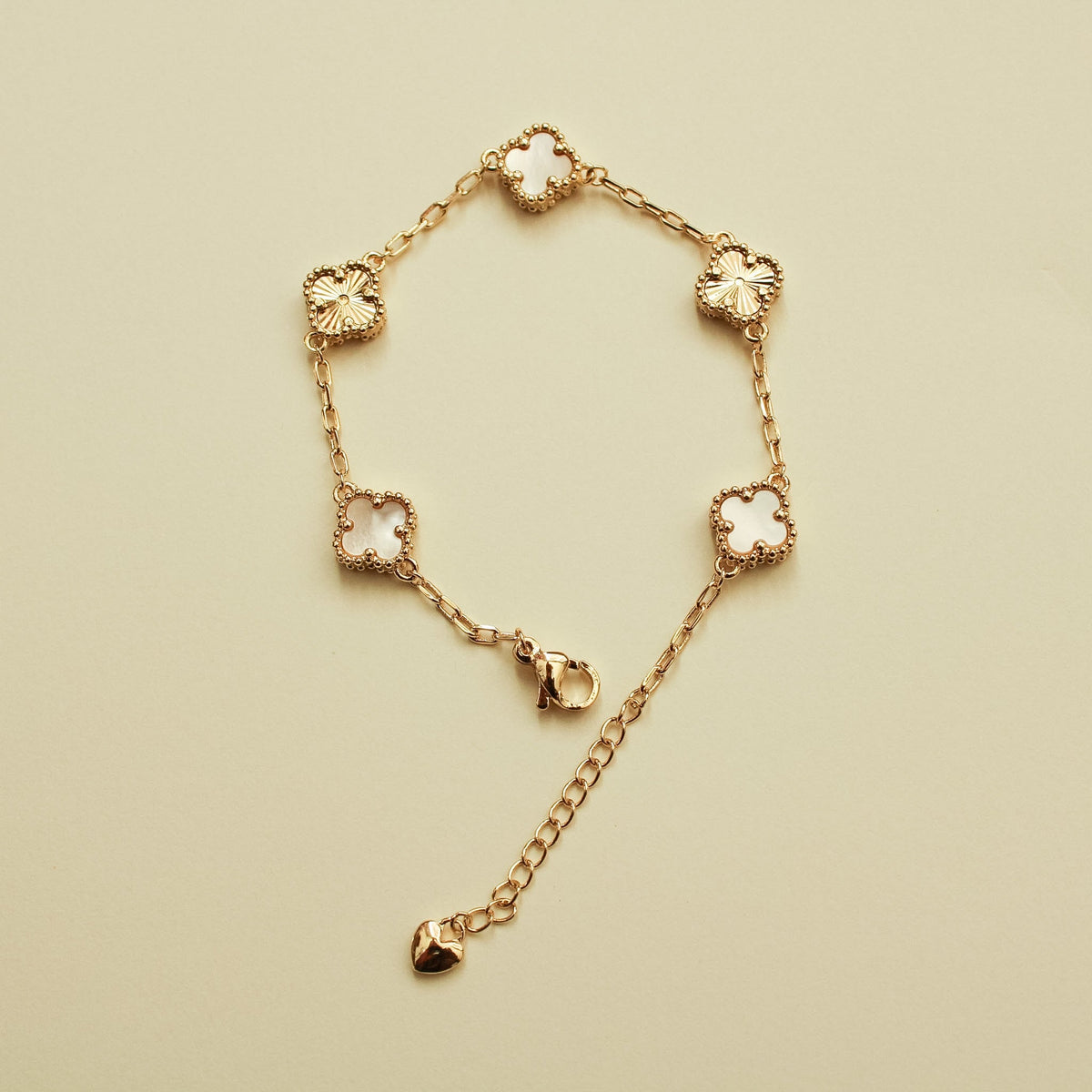 Gold bracelet with clover charms and mother-of-pearl inlays, heart drop detail