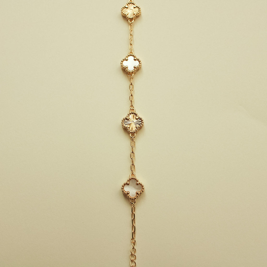 Gold bracelet with alternating clover charms and mother-of-pearl inlays, spaced chain links