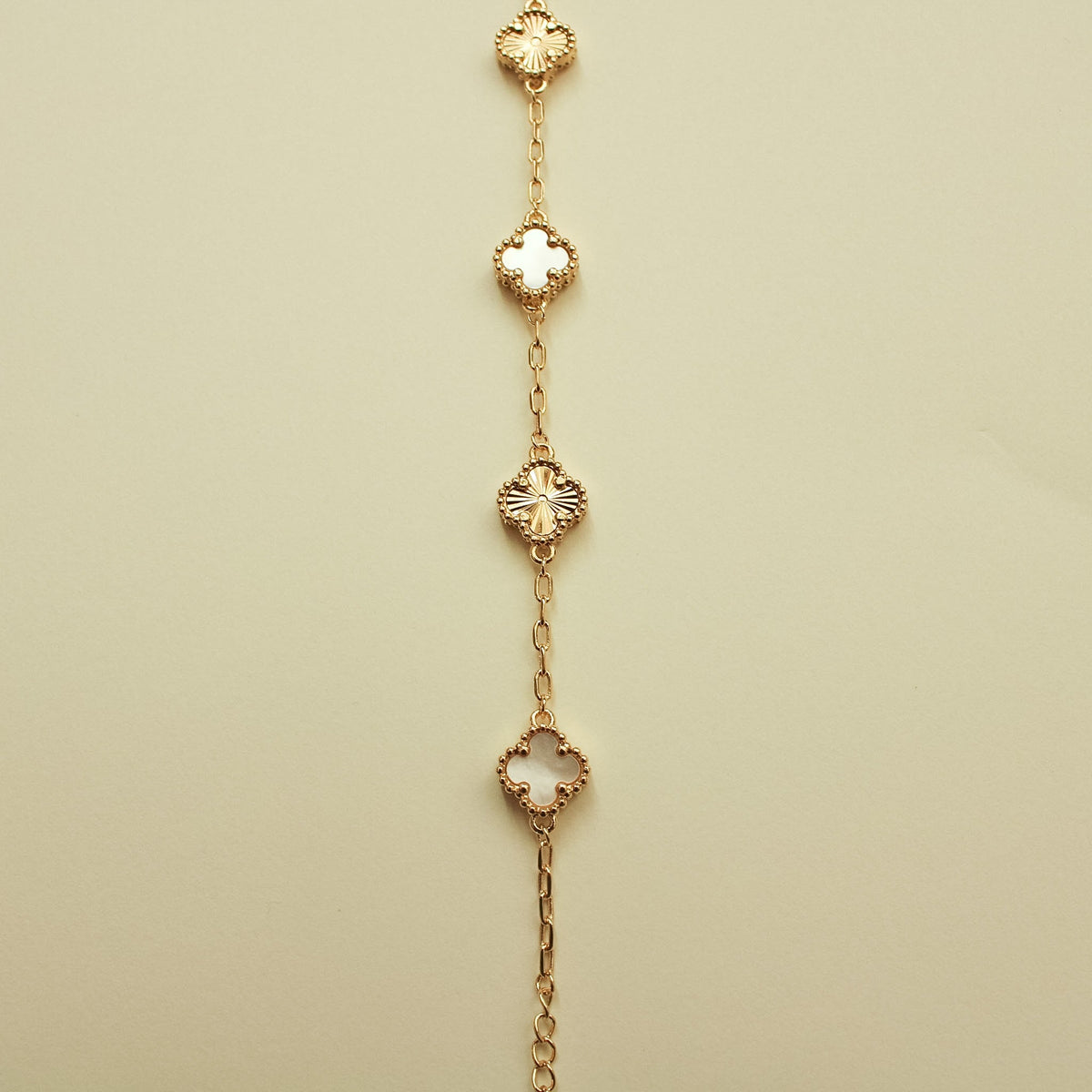 Gold bracelet with alternating clover charms and mother-of-pearl inlays, spaced chain links