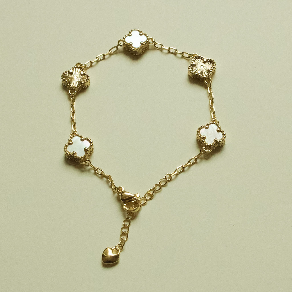 Gold-tone bracelet with clover charms, heart drop, and mother-of-pearl inlay