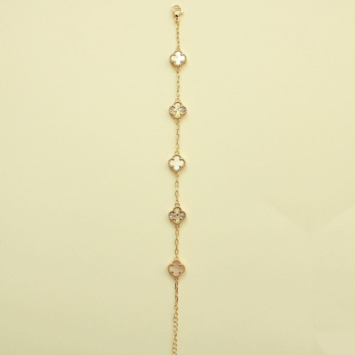 Gold bracelet hanging view with multiple clover charms and mother-of-pearl inlays