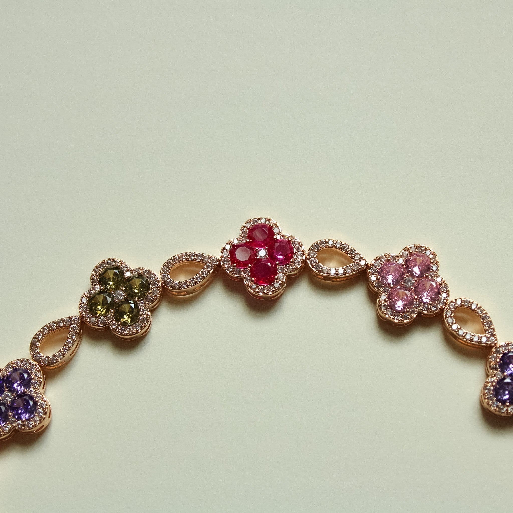 Gold-tone clover CZ bracelet with red, pink, and purple stones on oval links