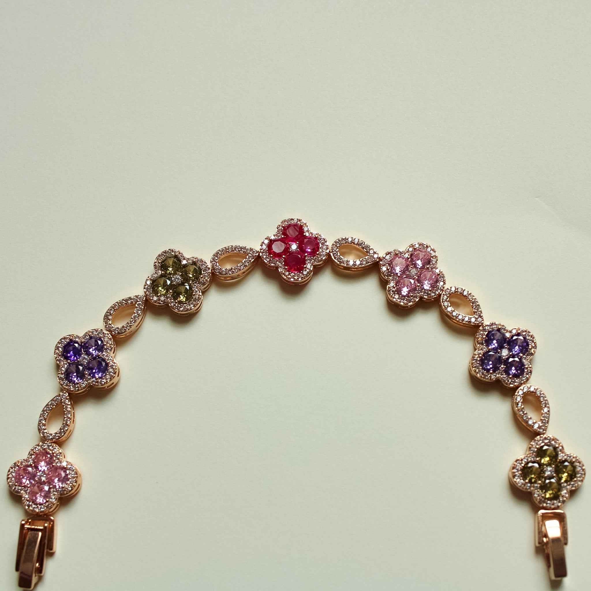 Gold-tone clover CZ bracelet with multicolor flower clusters and dangling end charms