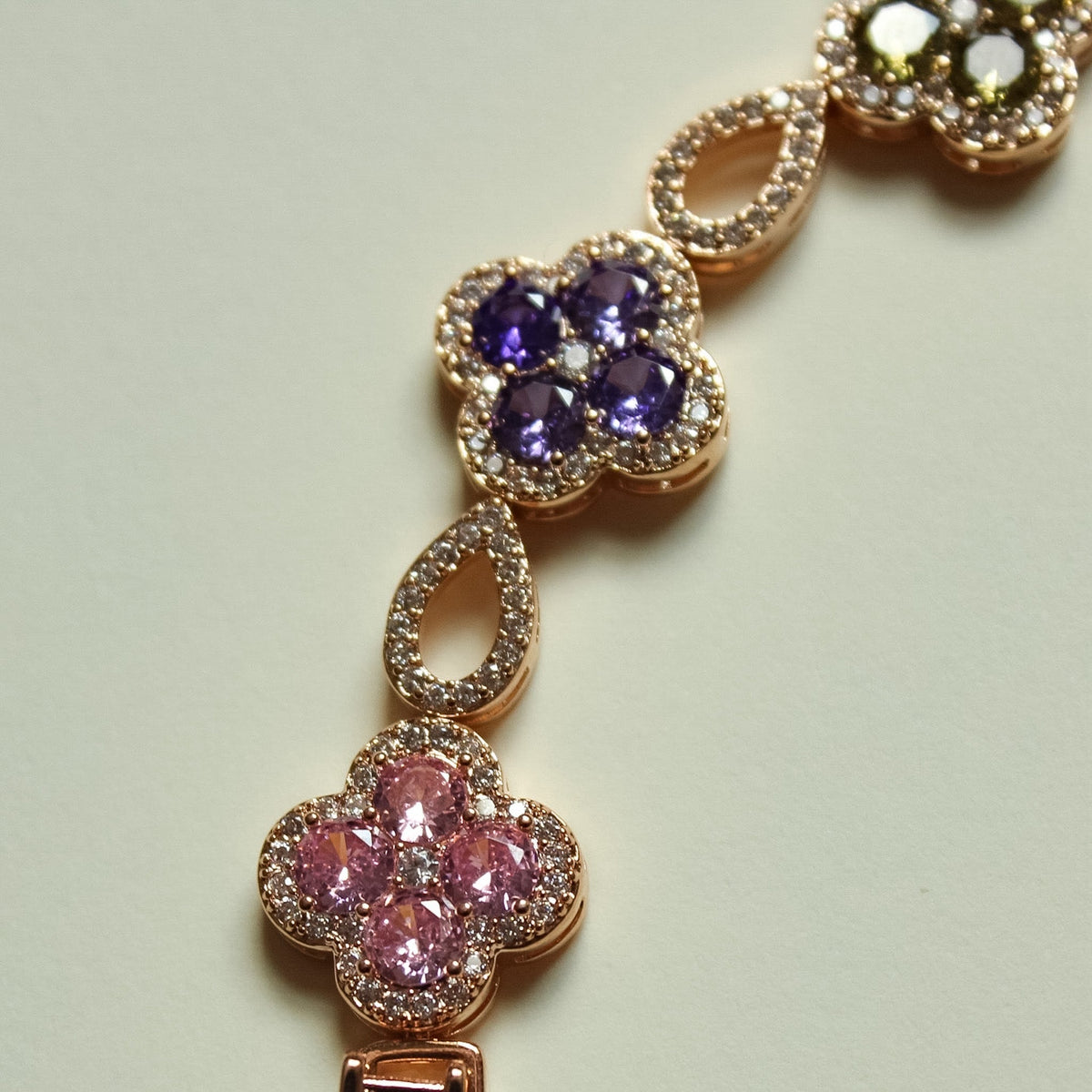 Gold-tone clover CZ bracelet with purple and pink flower stations and sparkle links