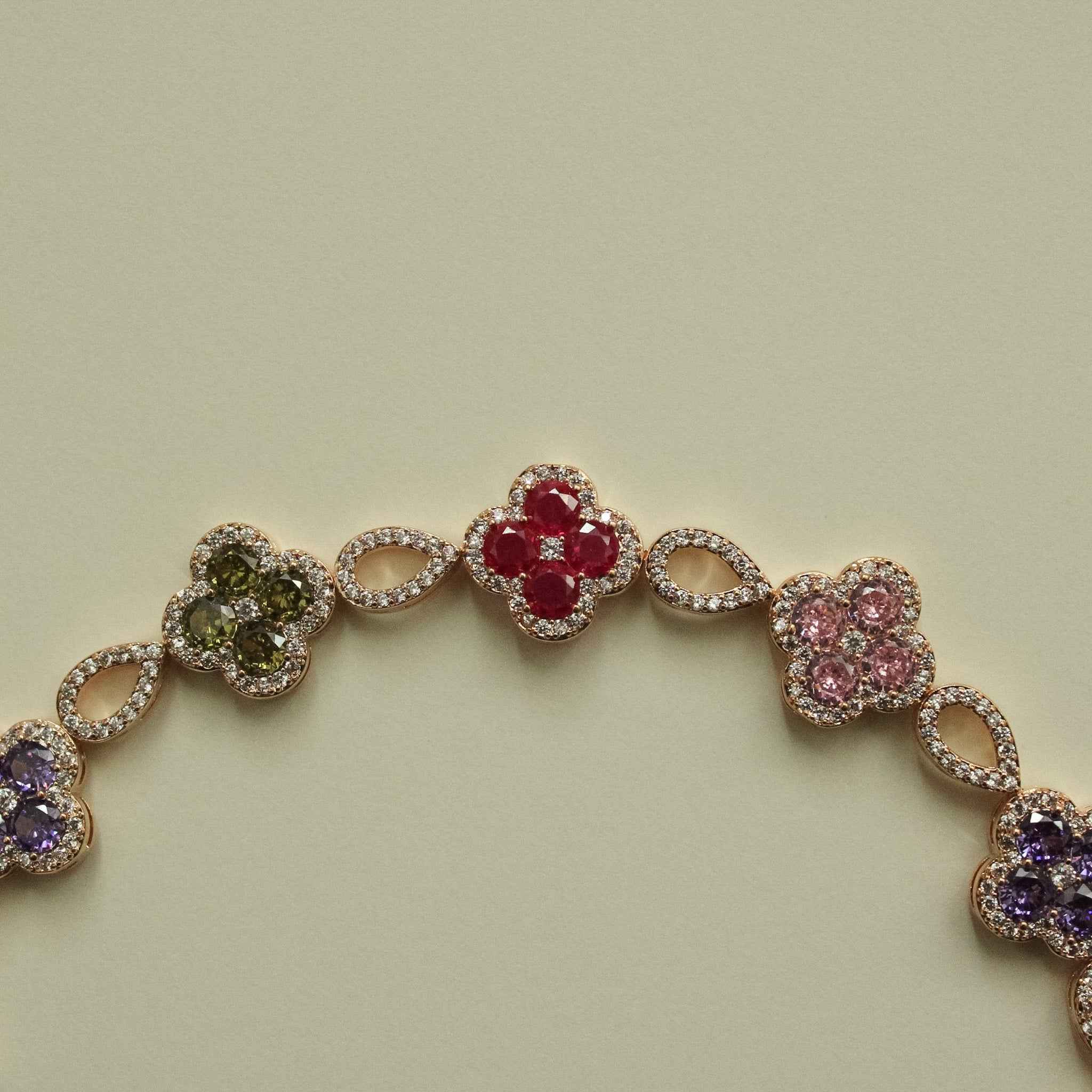 Gold-tone clover CZ bracelet with dark green, red, pink, and purple flower links