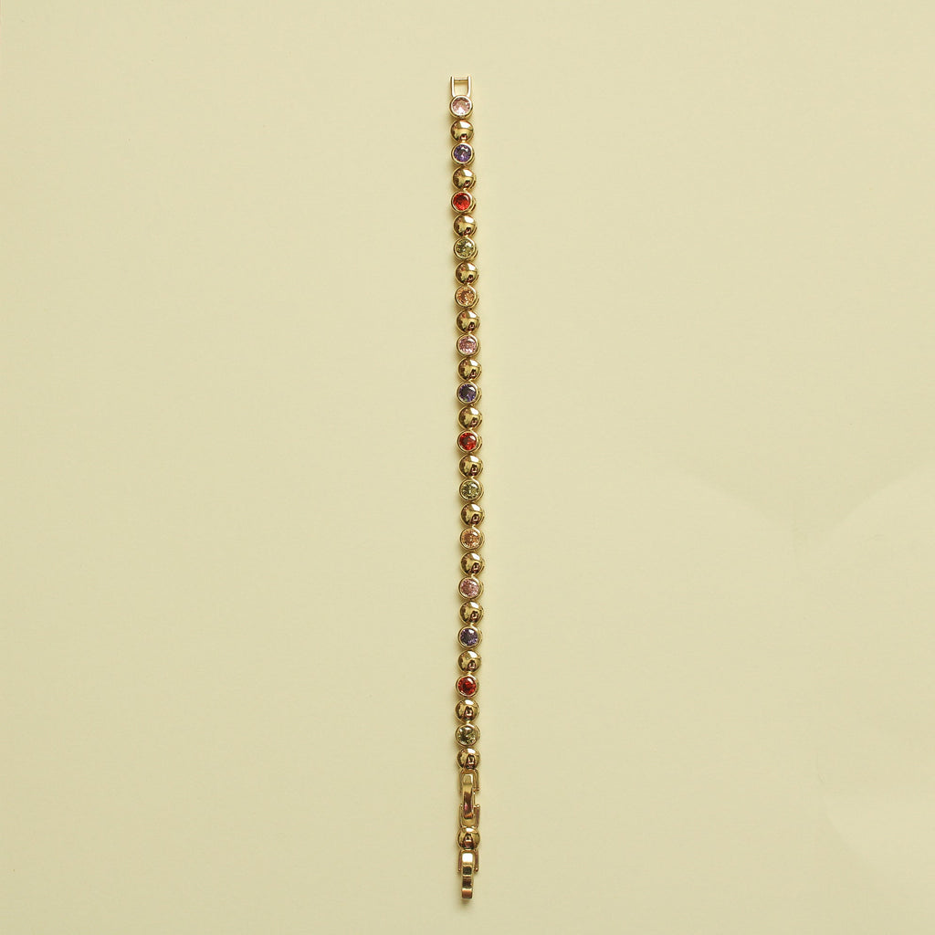 Gold tennis bracelet with multicolor CZ stones in a straight line on a chain bar