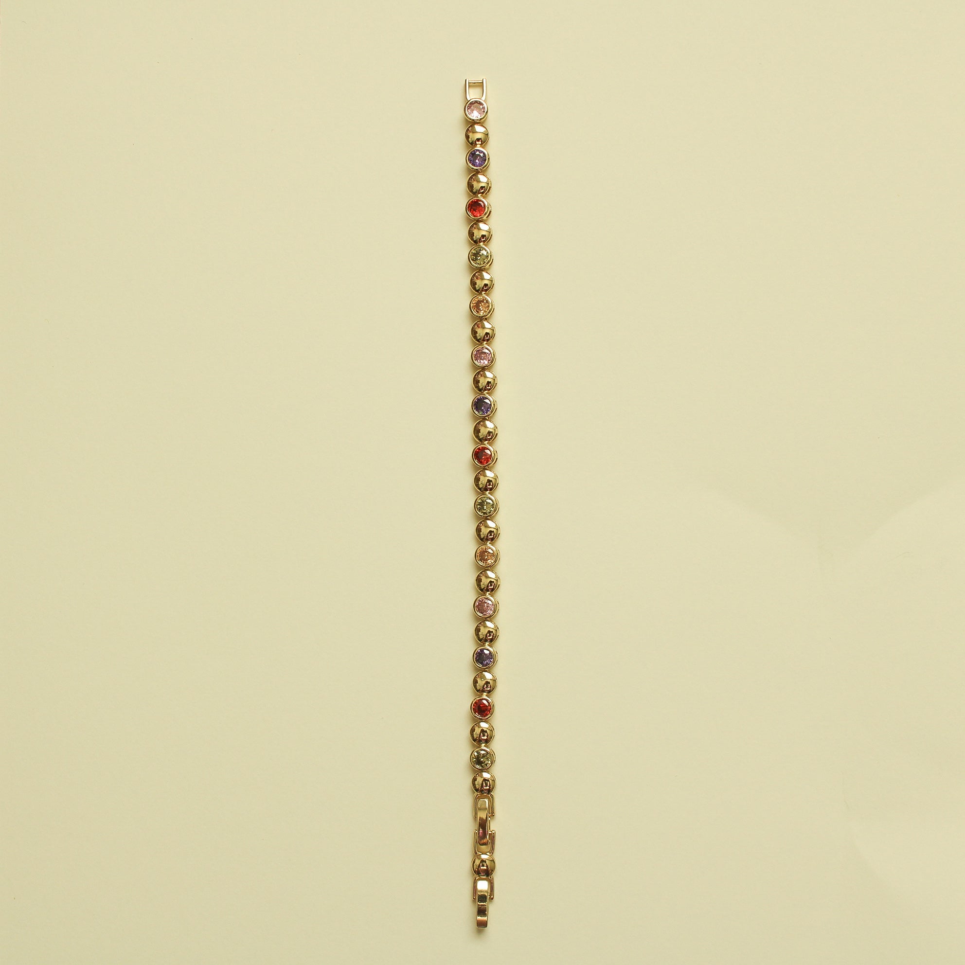 Gold tennis bracelet with multicolor CZ stones in a straight line on a chain bar