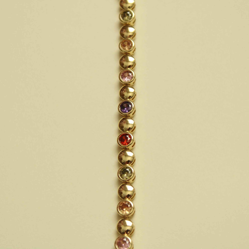 Gold tennis bracelet strand with small multicolor CZ stones set along beaded links