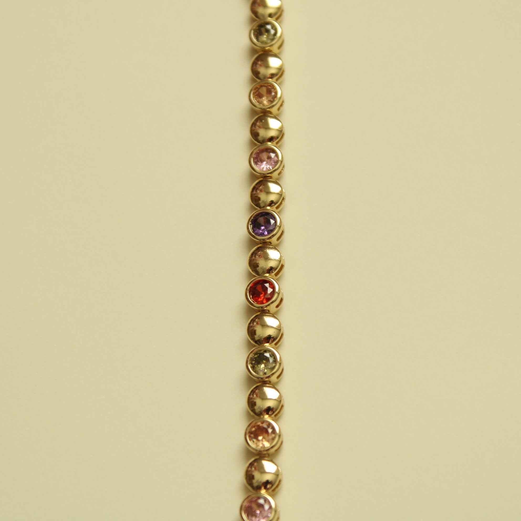 Gold tennis bracelet strand with small multicolor CZ stones set along beaded links