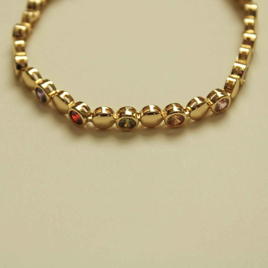 Gold tennis bracelet with multicolor CZ dome stones across scalloped link row
