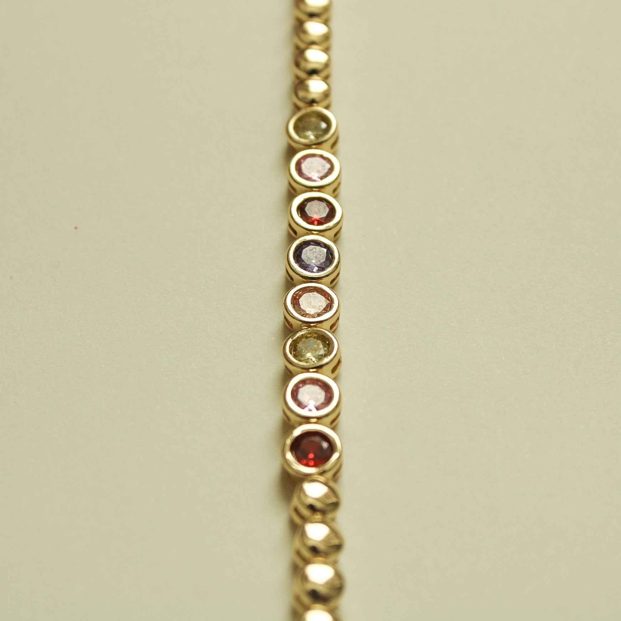 Gold tennis bracelet close-up of multicolor circular CZ bezels