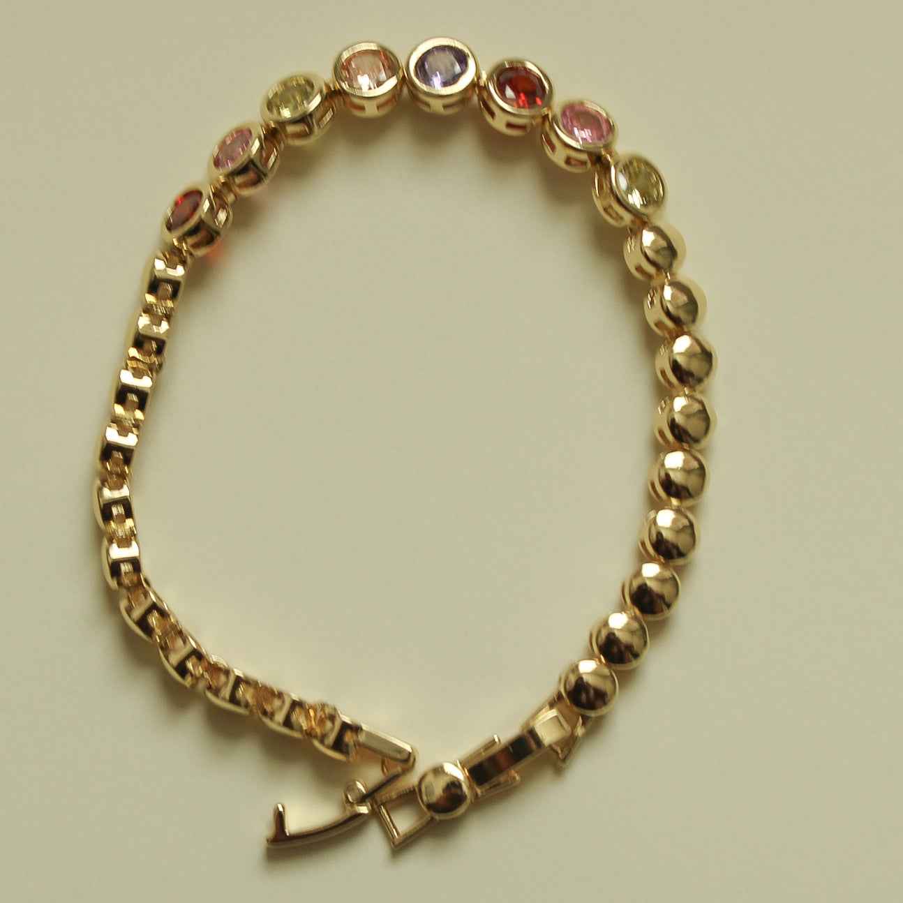 Gold beaded tennis bracelet with multicolor CZ bezel stones and toggle clasp