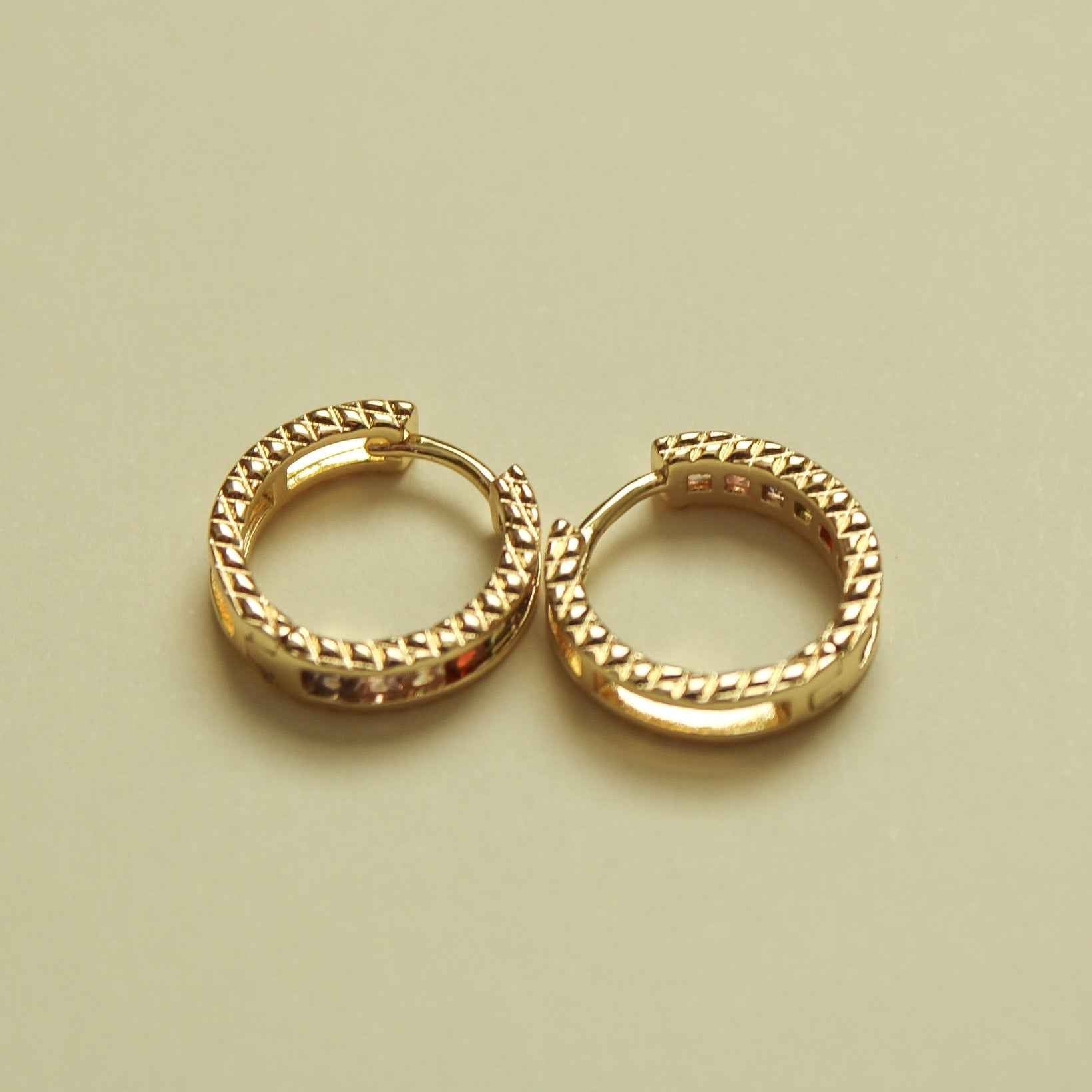Gold-tone huggie hoop earrings with clear CZ accents, pair view