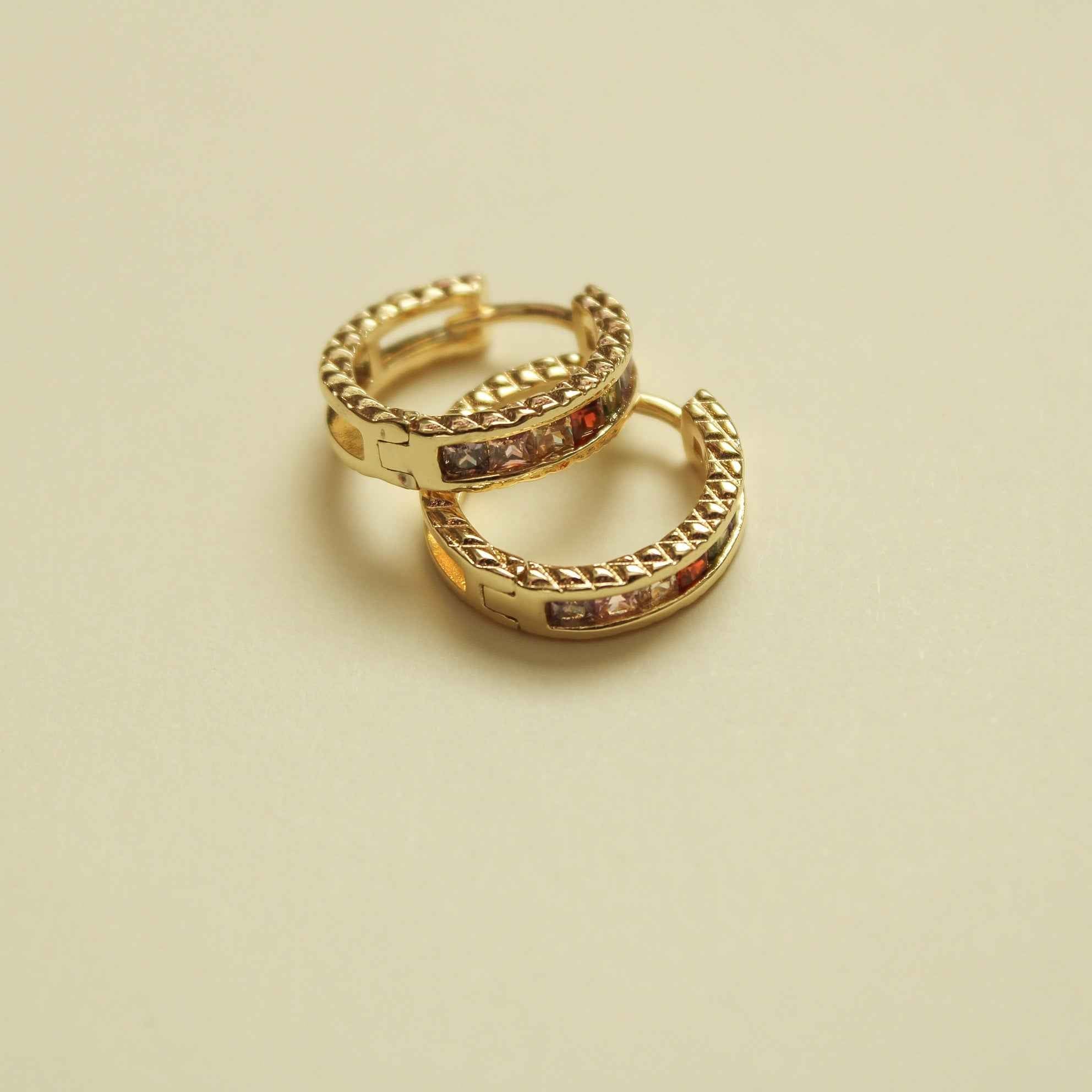 Gold-tone huggie hoop earrings with multicolor CZ stones, angled pair view