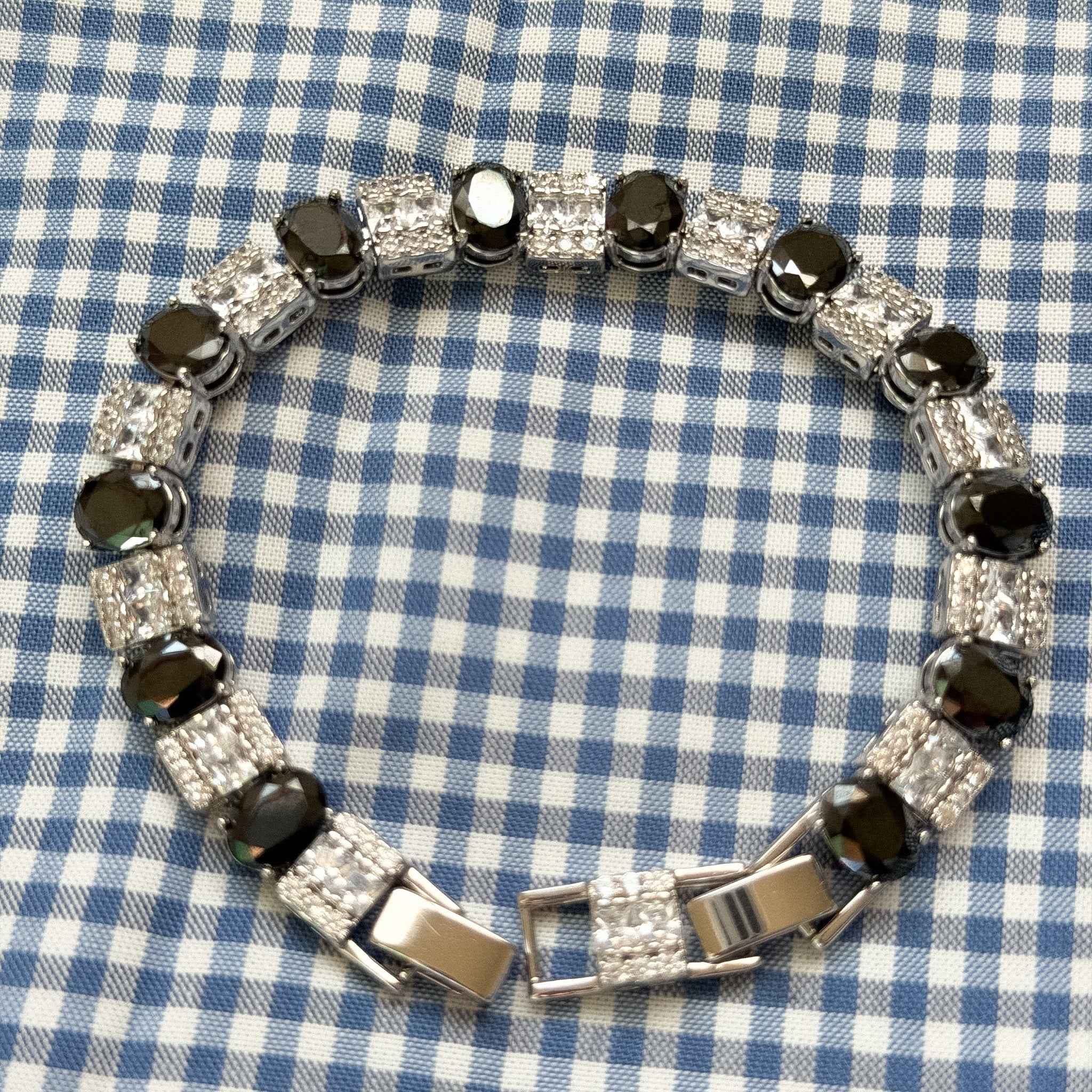 Tennis bracelet clasp view with black stones, clear CZ squares, and silver links