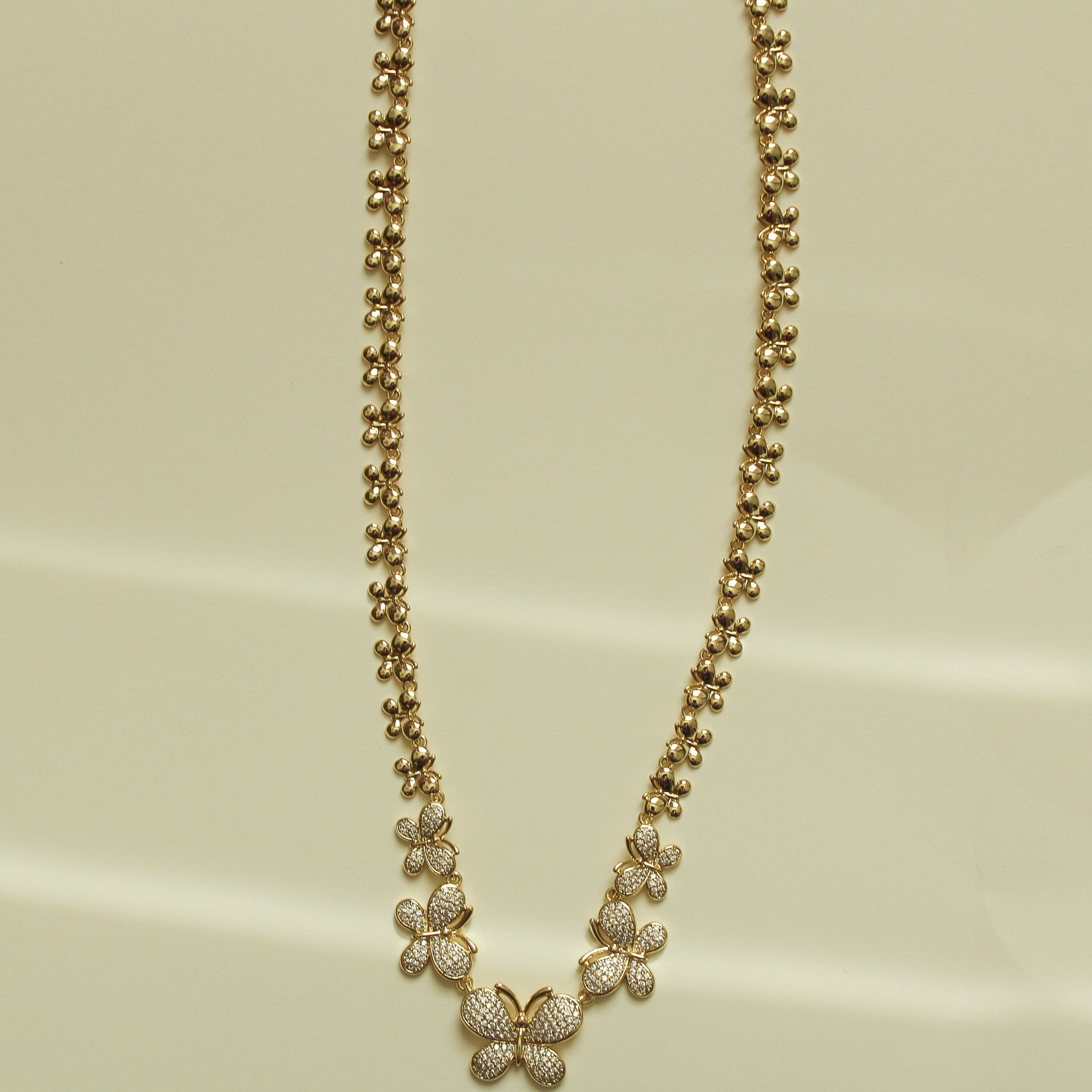 Gold butterfly necklace with small pavé butterfly charms along ball-bead chain