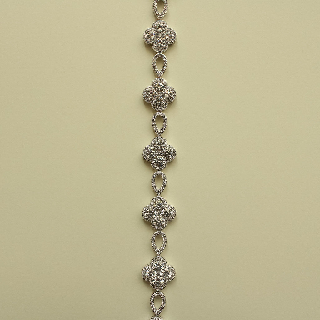 Row of silver-tone CZ clover flower charms connected by oval drop links