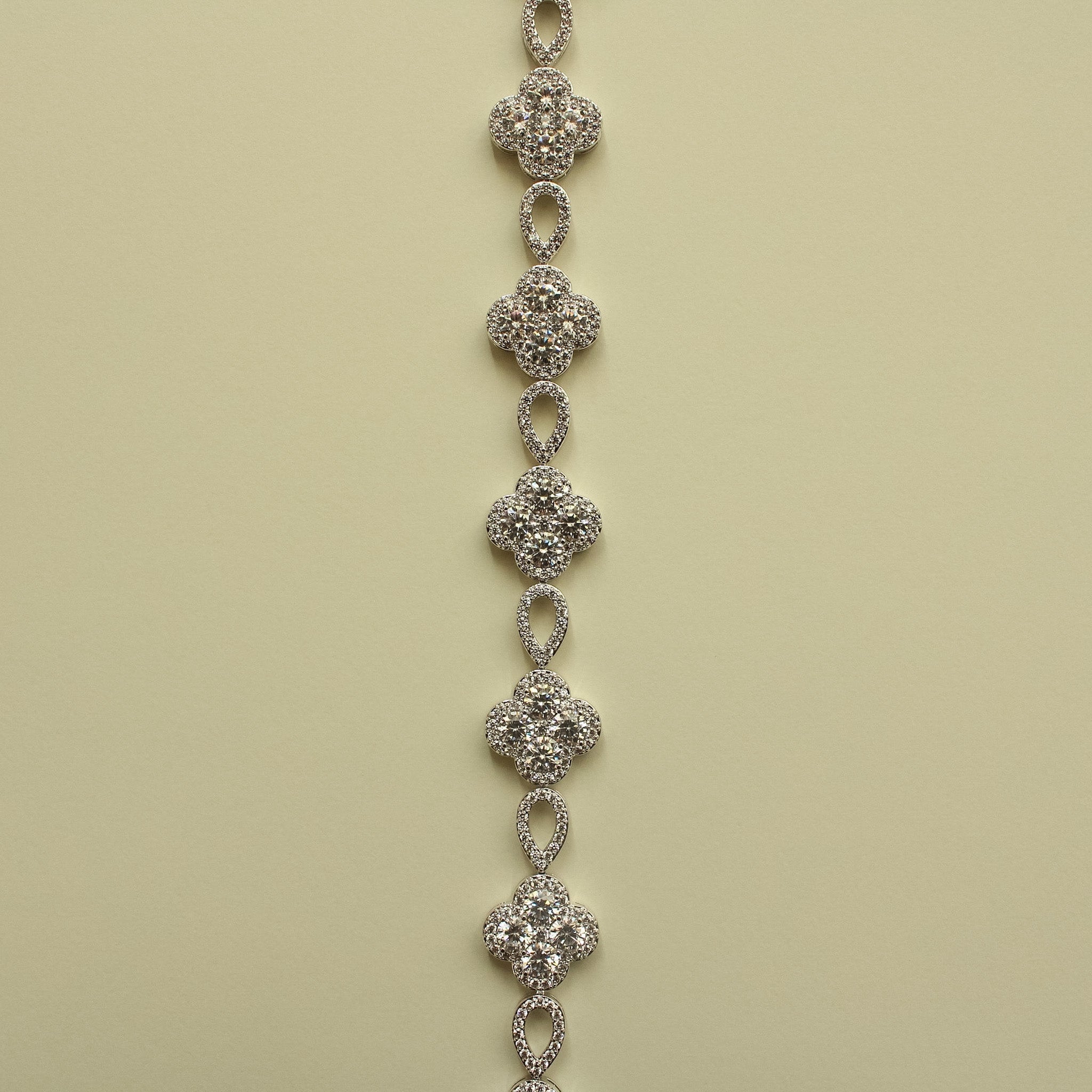 Row of silver-tone CZ clover flower charms connected by oval drop links