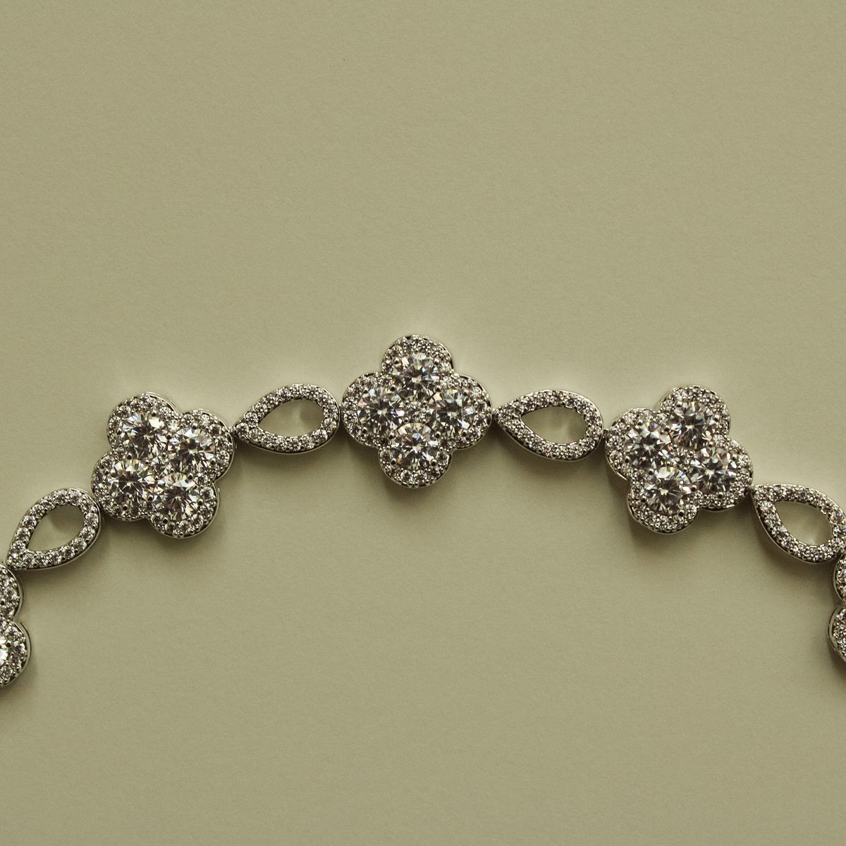 Close-up of silver-tone CZ clover bracelet section with oval spacer links