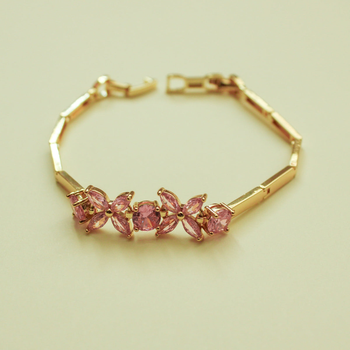 Gold-tone bracelet with five pink and lilac flower gems in a row