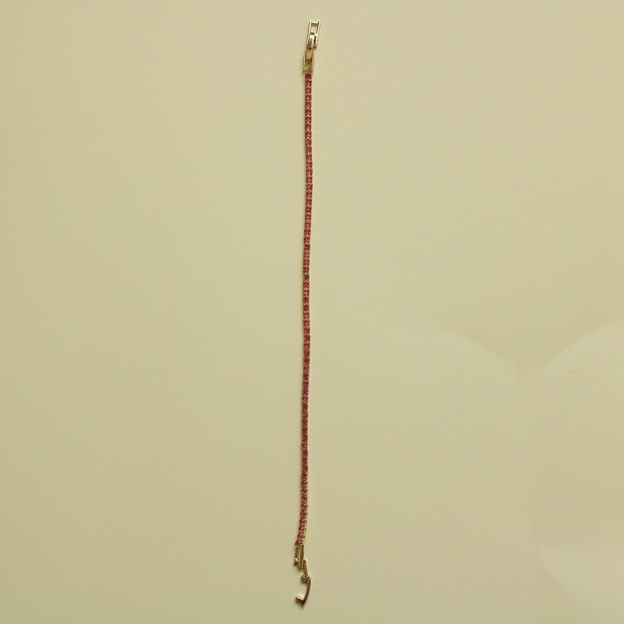 Gold-tone tennis bracelet with pink CZ row and open hook clasp at one end.